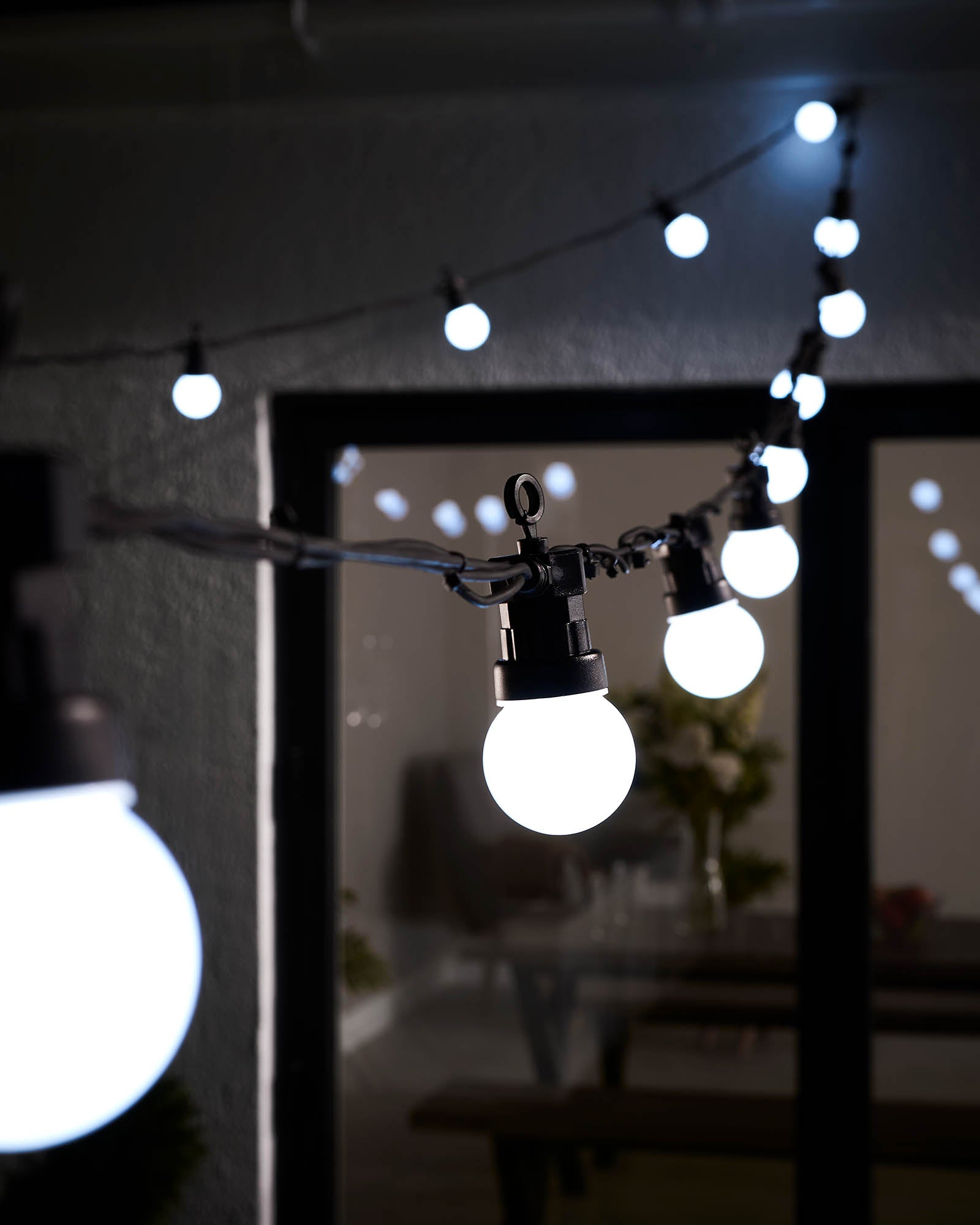 String lights with multi-colored bulbs hanging outdoors, displaying a variety of colors including green, yellow, and blue.