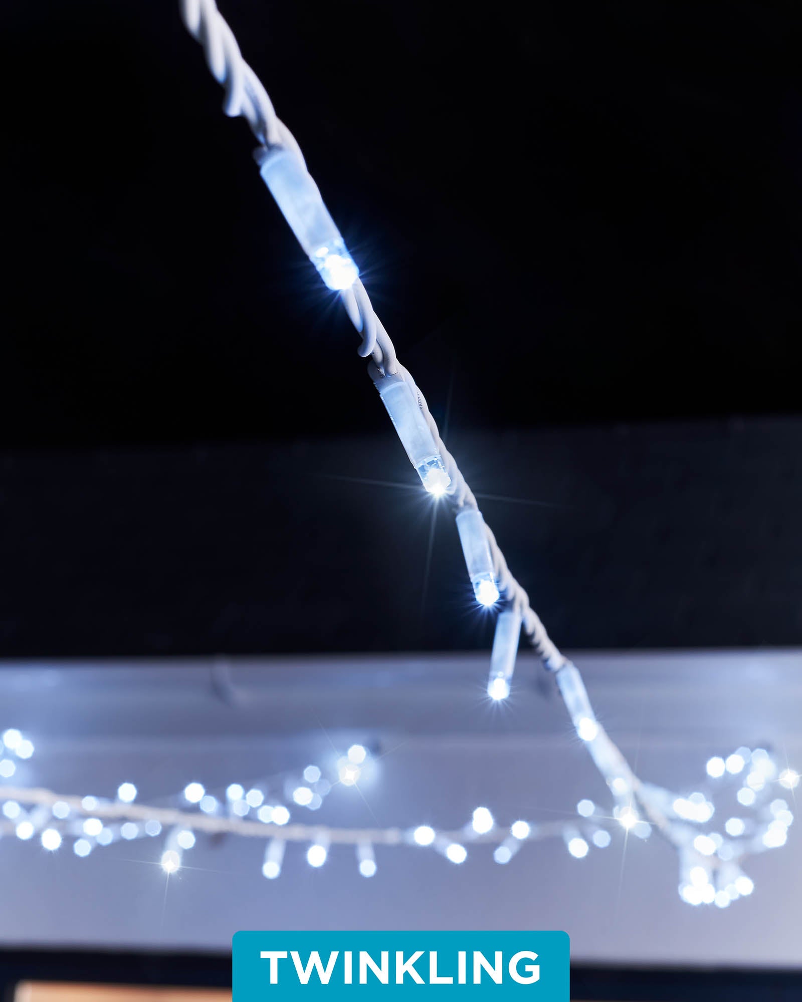 A close-up of white LED string lights with a focus on the twinkling feature, displaying the lights in an outdoor setting.