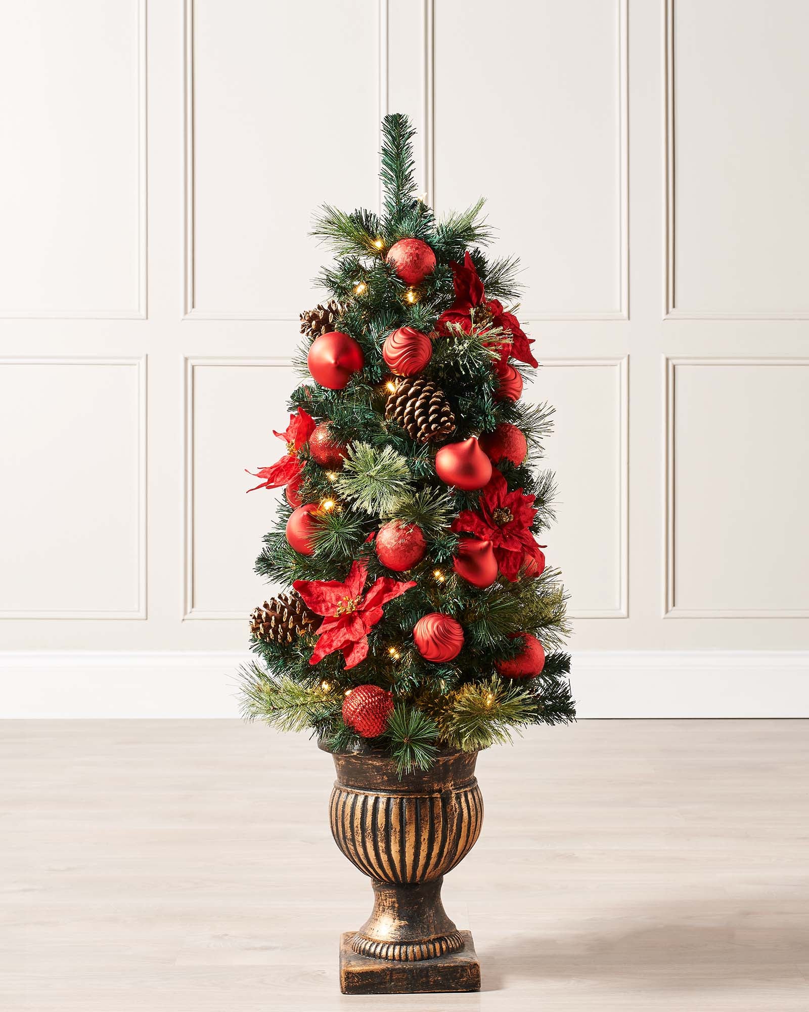 4-foot pre-lit potted Christmas tree with 140 PVC tips, warm white LED lights, red and silver baubles, pinecones, and berries, set against a white background.