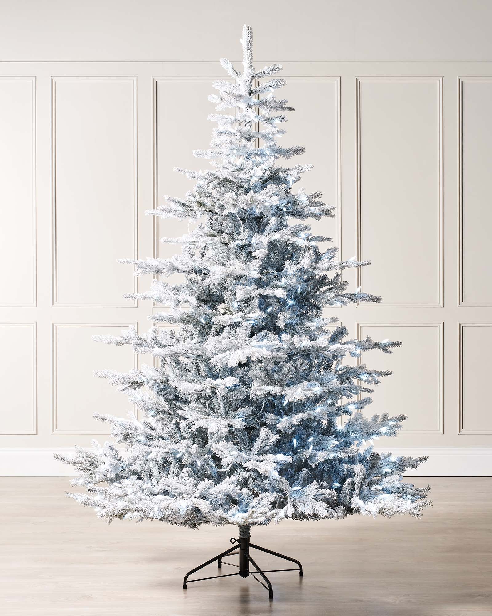 6-foot pre-lit snow flocked spruce Christmas tree with dense white PE and PVC branches. The tree features 350 cool white candle LED lights, a snow-flocked finish, and stands on a metallic base against a neutral background.