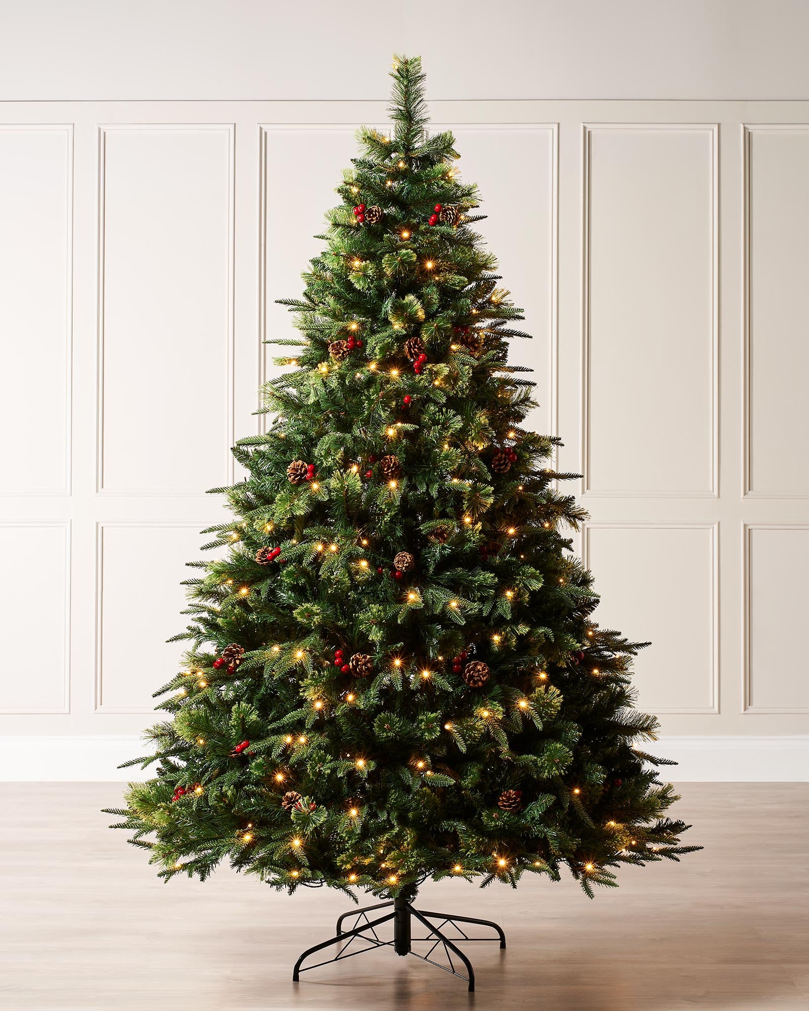 Pre-lit Christmas tree with mixed PE and PVC tips, decorated with realistic berries and pinecones, illuminated by warm white LED lights, standing against a neutral background.