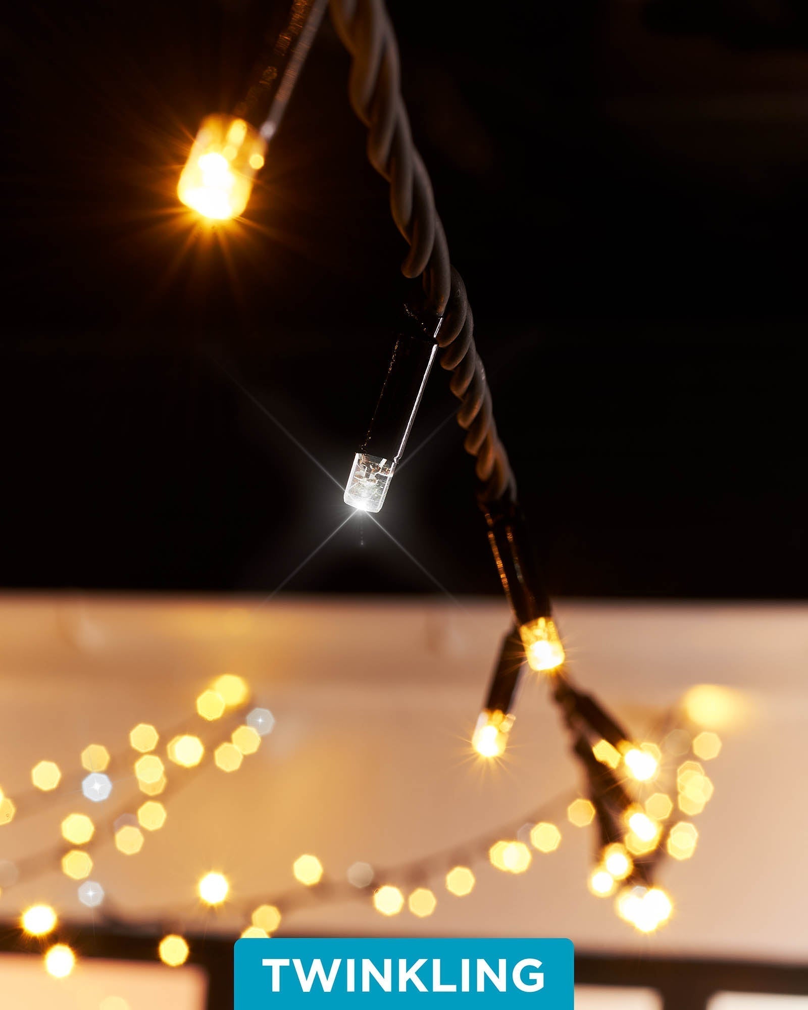 Close-up of connectable twinkle string lights with warm white and white LEDs, showcasing the twinkle effect. The image is taken during the evening with a blurred background.