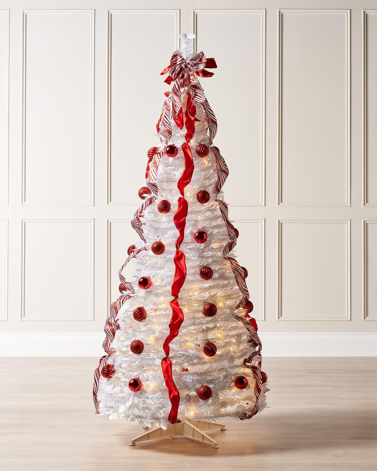 6-foot pre-lit pop-up Christmas tree with red and white decorations, including baubles and ribbons, illuminated by warm white LED lights.