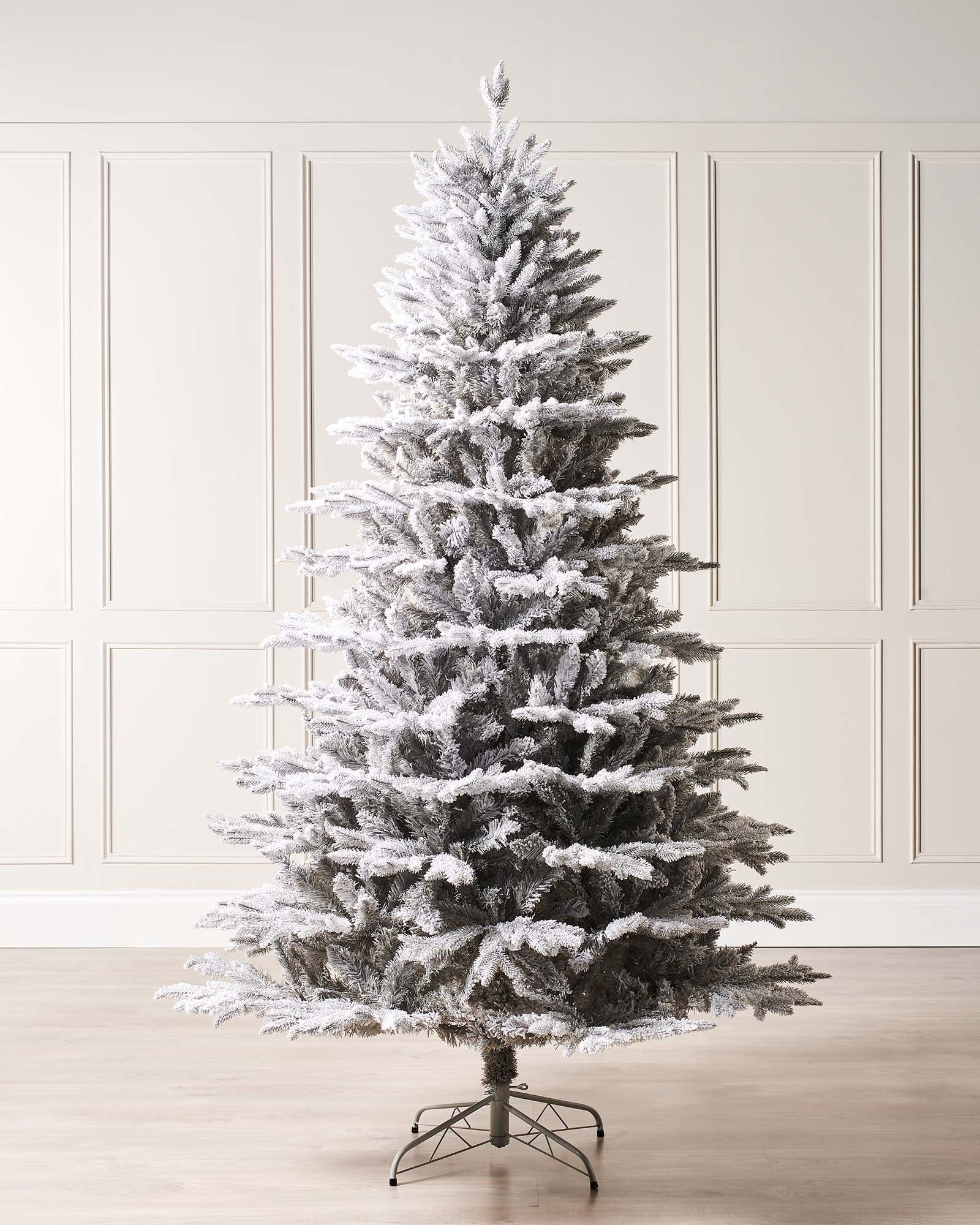 Snow-flocked grey fir artificial Christmas tree with soft grey tones, mixed tips, and a foldable metal stand—featuring a frosted, wintry look that blends traditional charm with modern elegance, perfect for stylish indoor holiday displays.