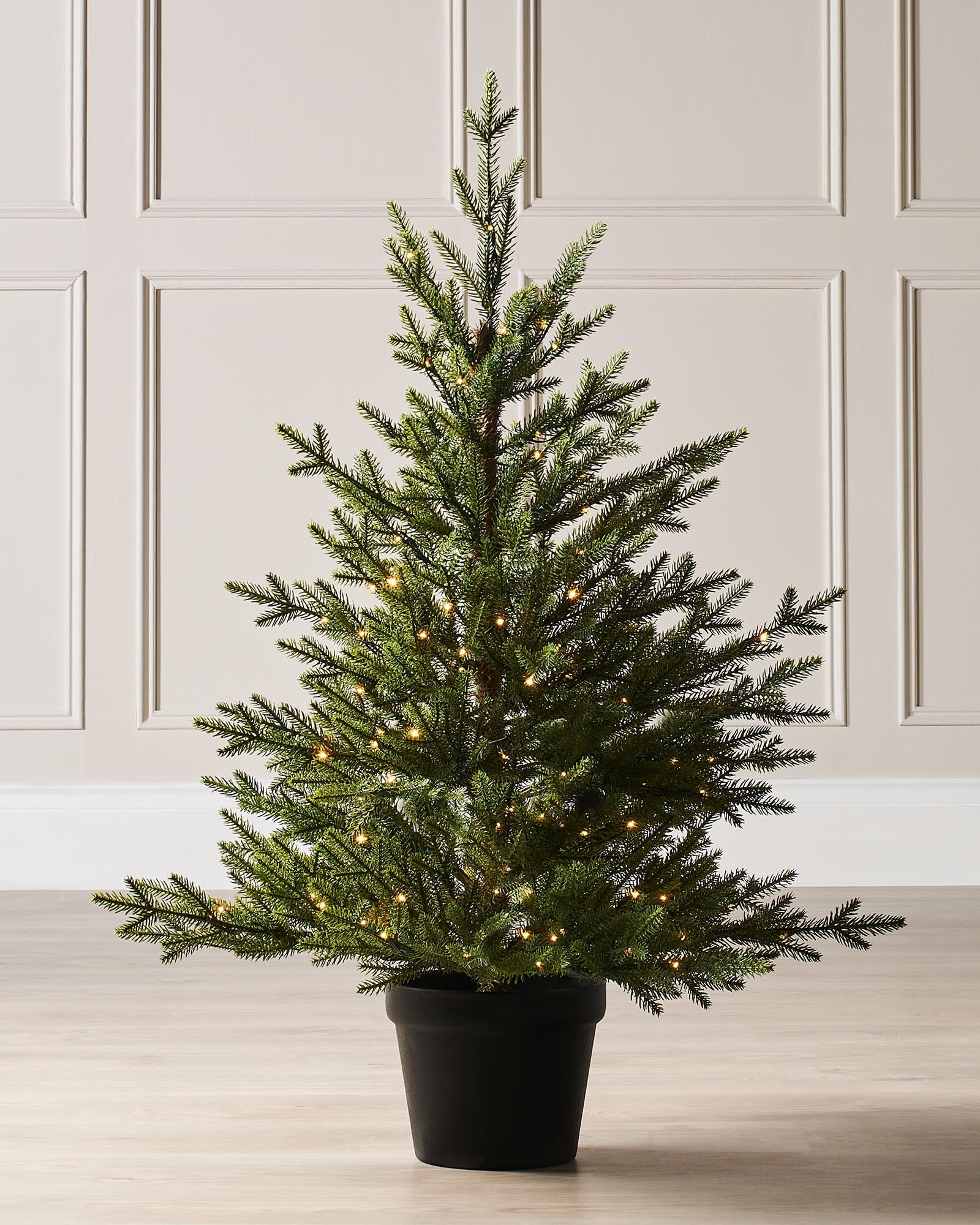 3-foot Douglas Fir potted Christmas tree with realistic PE tips, adorned with delicate copper wire micro LED lights, standing indoors in a black pot.