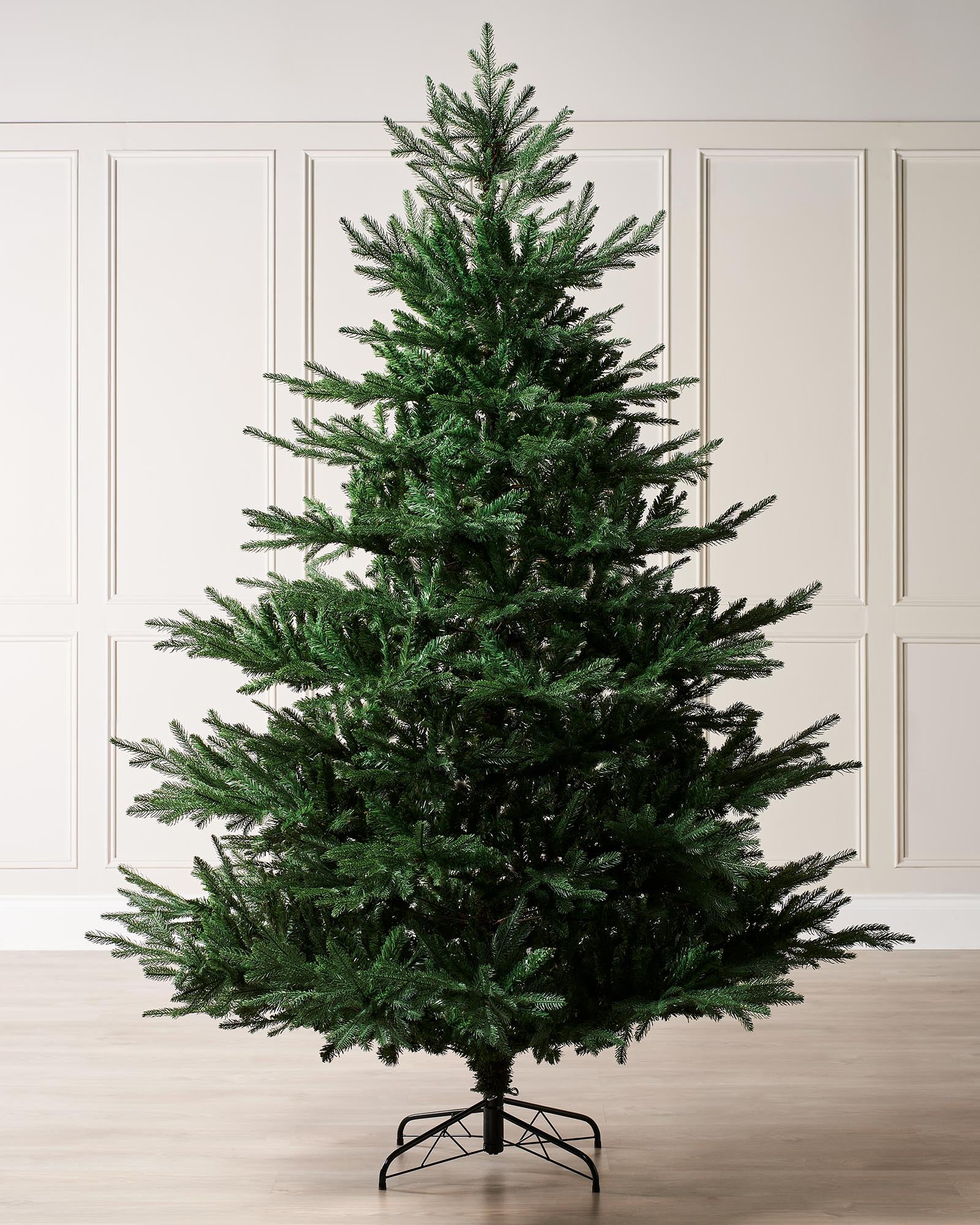 Artificial Northern Fir Christmas tree with a full canopy of lush green needles, featuring a lifelike dense appearance and foldable hinged branches for easy assembly and storage—perfect as a traditional yet modern centerpiece for festive indoor décor.