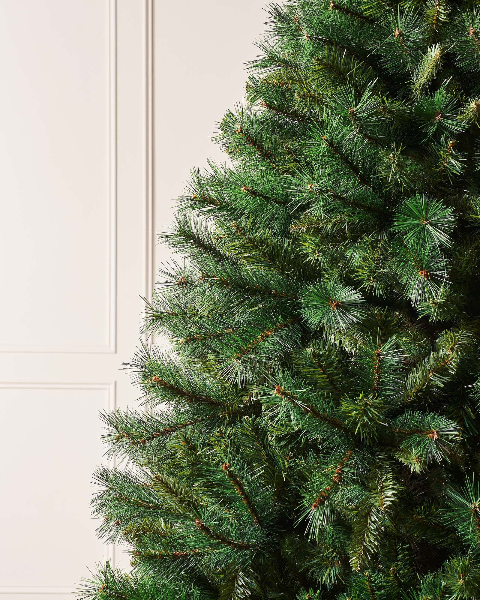 Full-bodied Victorian Pine artificial Christmas tree with dense green needles and a sturdy metal stand, showcasing a realistic and classic design that brings timeless elegance and festive charm to any indoor space.