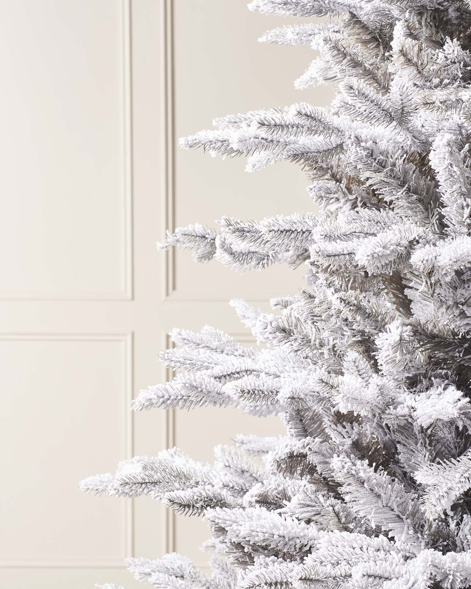 Snow-flocked grey fir artificial Christmas tree with soft grey tones, mixed tips, and a foldable metal stand—featuring a frosted, wintry look that blends traditional charm with modern elegance, perfect for stylish indoor holiday displays.