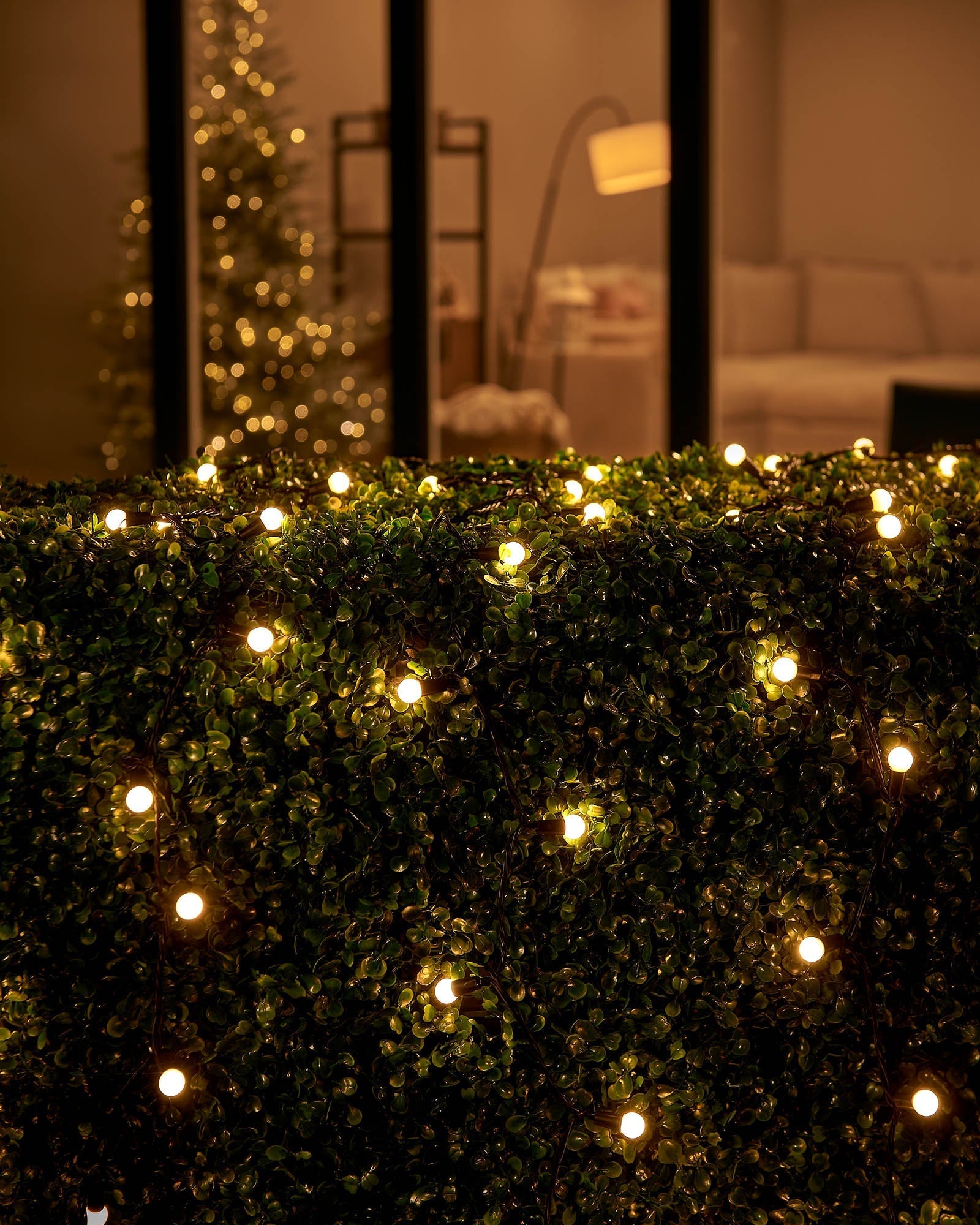 String of warm white LED lights with matte white berry caps, depicting a soft glow amidst green foliage.