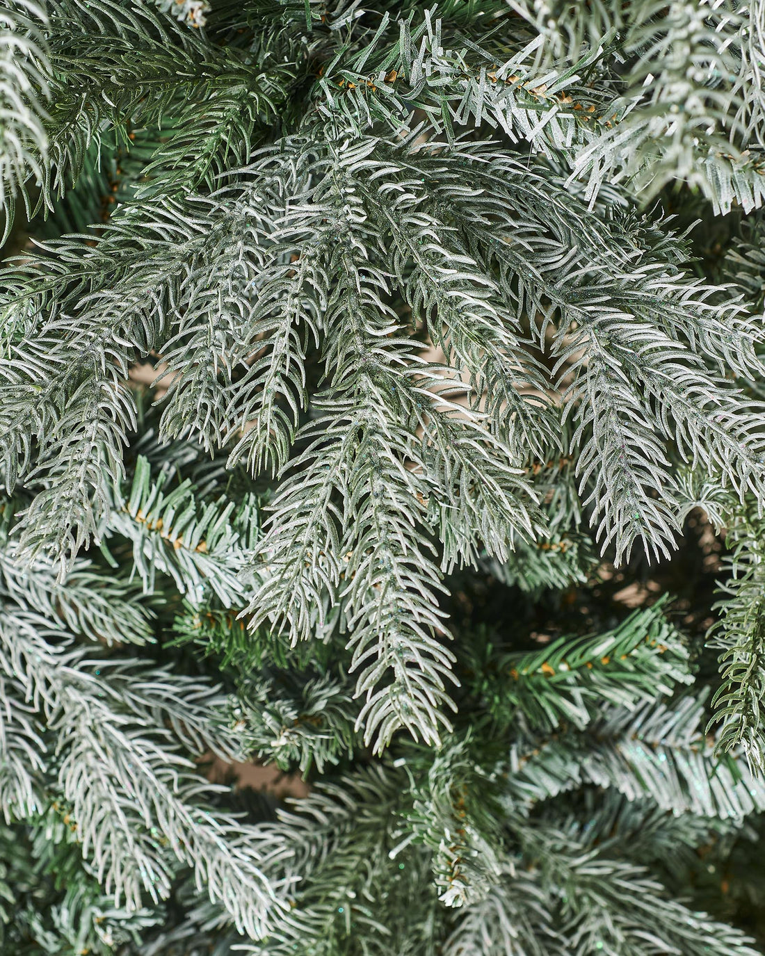 A frosted Siberian Mixed Pine Christmas tree featuring white glitter-tipped branches and fern green foliage, complete with a foldable metal stand. This lifelike, easy-to-assemble tree blends traditional charm with modern elegance, offering a sparkling, customizable canvas for your festive decorations.