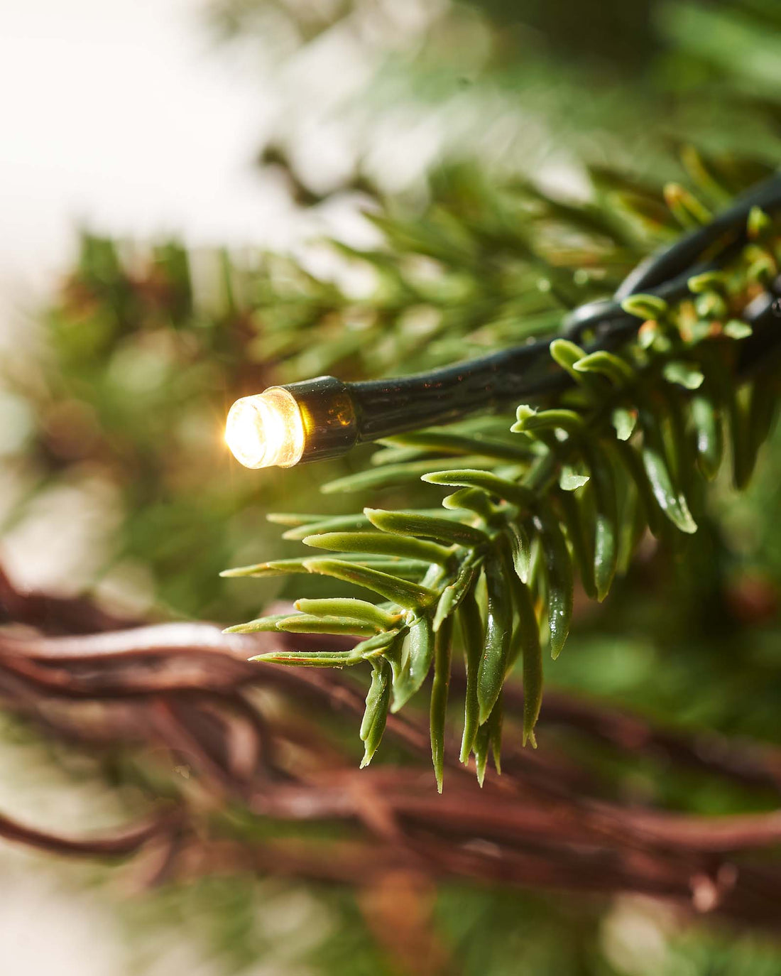4.5-foot pre-lit potted Christmas tree with lush green mixed PE and PVC foliage, warm white LED lights, red berries, and natural brown pinecones, displayed indoors.