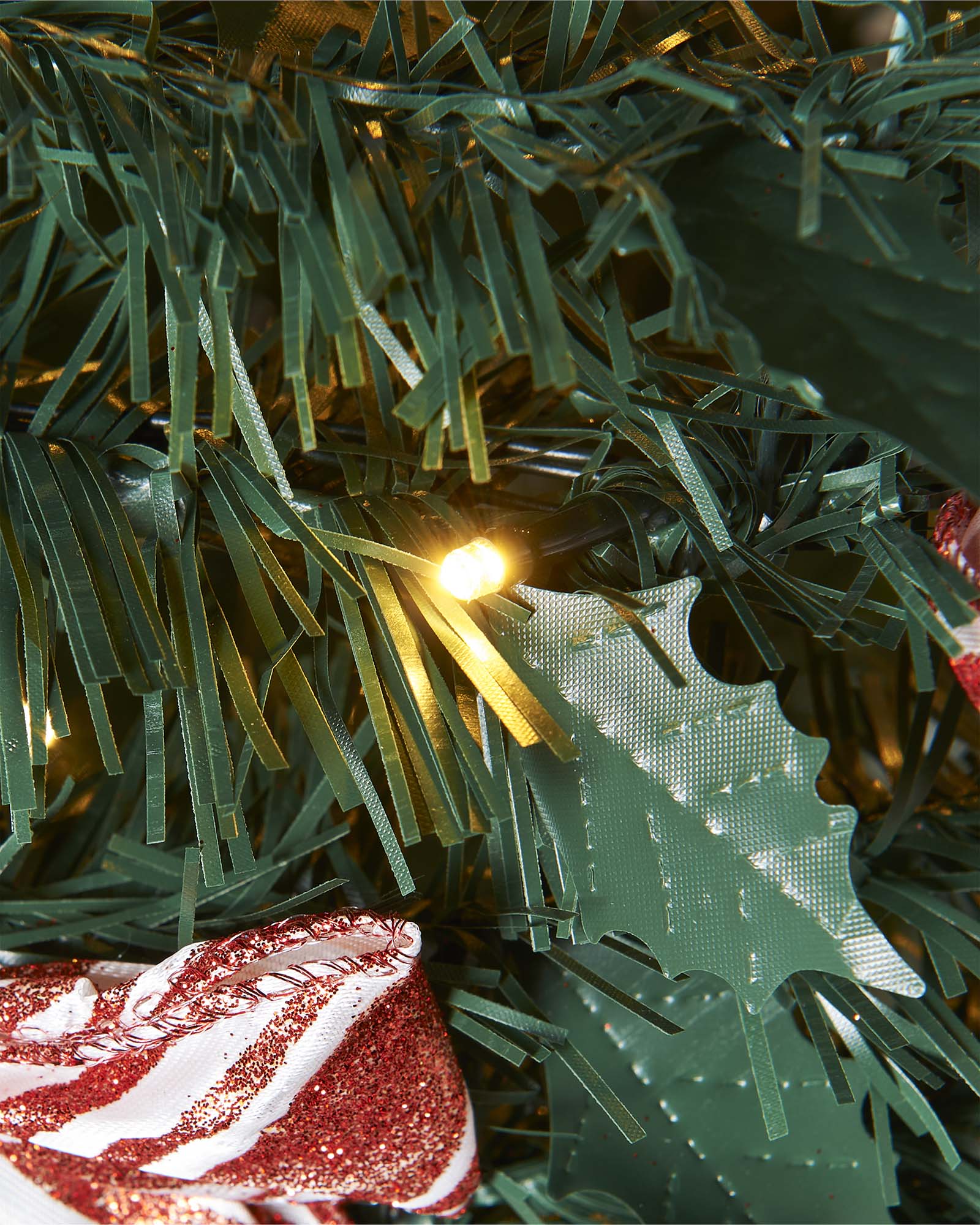Decorated Christmas tree with ribbons and ornaments against a white paneled wall.