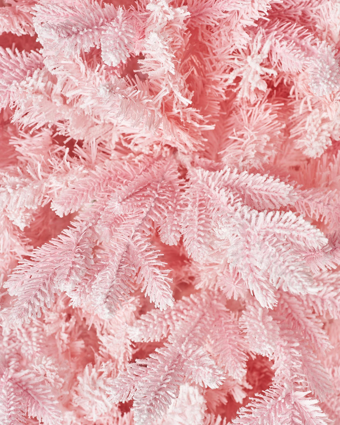 A 7-foot tall artificial pink Christmas tree with snow-flocked PE and PVC tips, set up in a room with white walls and a foldable base.