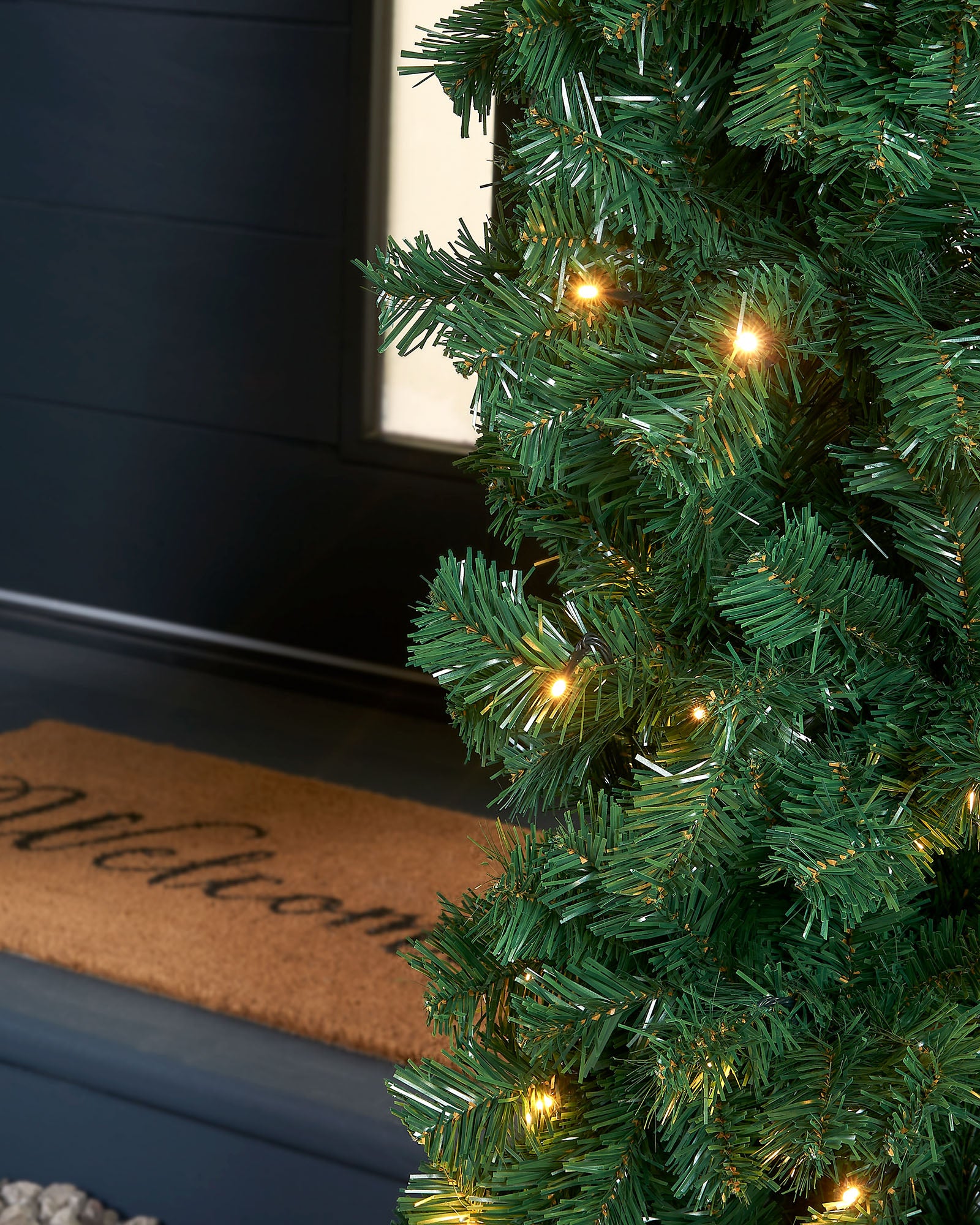 A close-up of a pre-lit, extra thick, mixed pine snow flocked garland with pinecones and berries, featuring warm white LED lights.