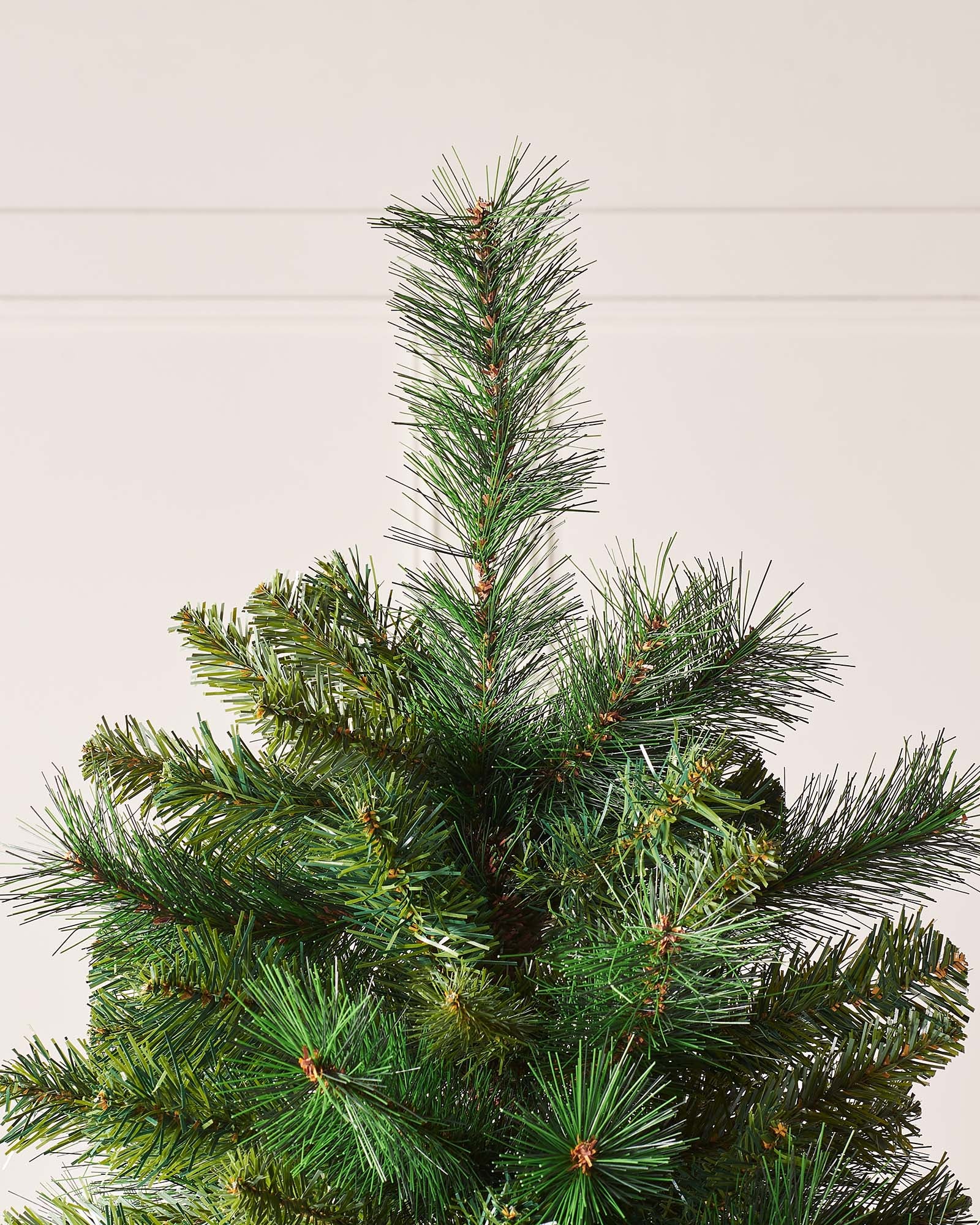 Full-bodied Victorian Pine artificial Christmas tree with dense green needles and a sturdy metal stand, showcasing a realistic and classic design that brings timeless elegance and festive charm to any indoor space.
