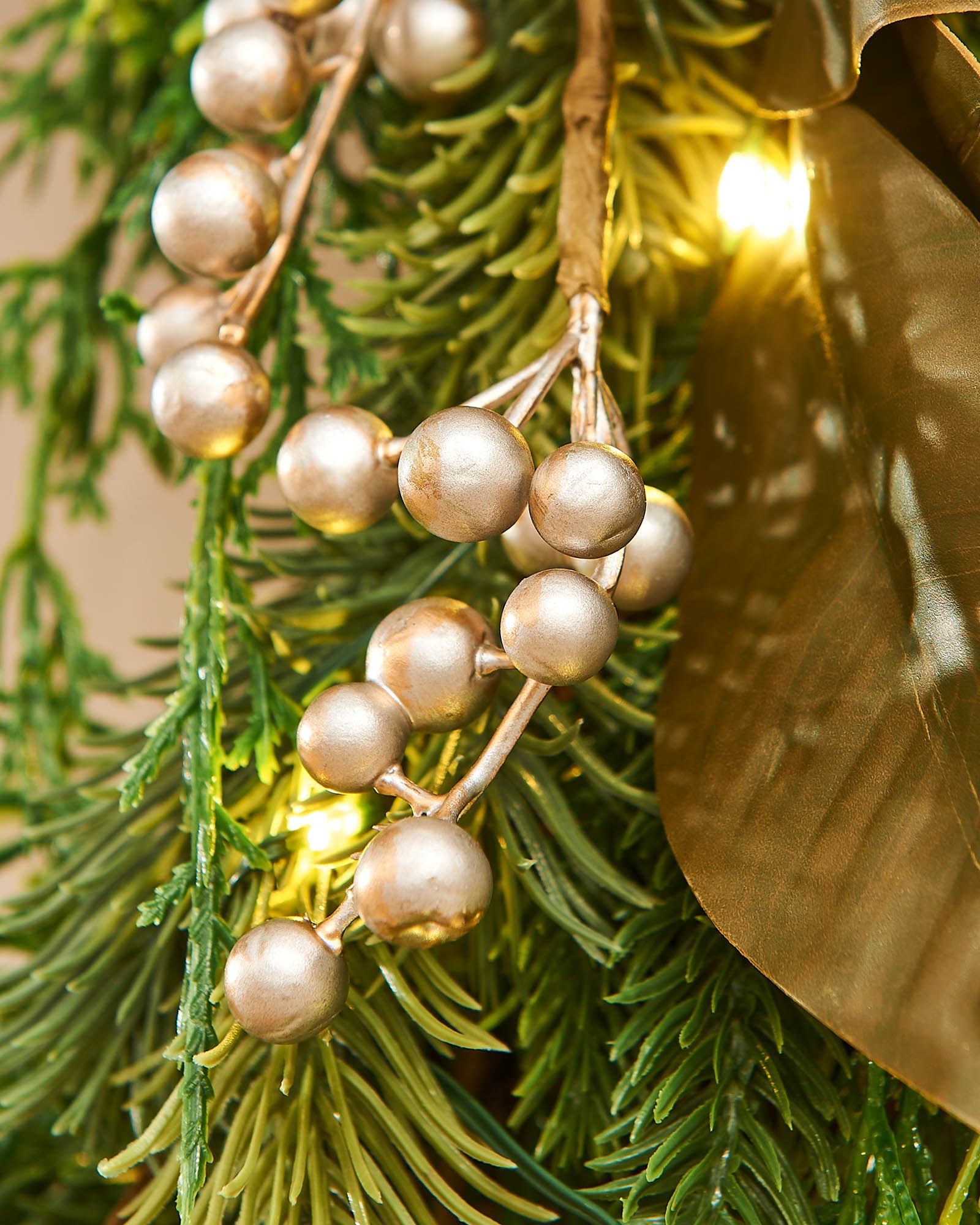 A festive Christmas wreath adorned with pinecones, gold berries, and LED lights, set against a white background.