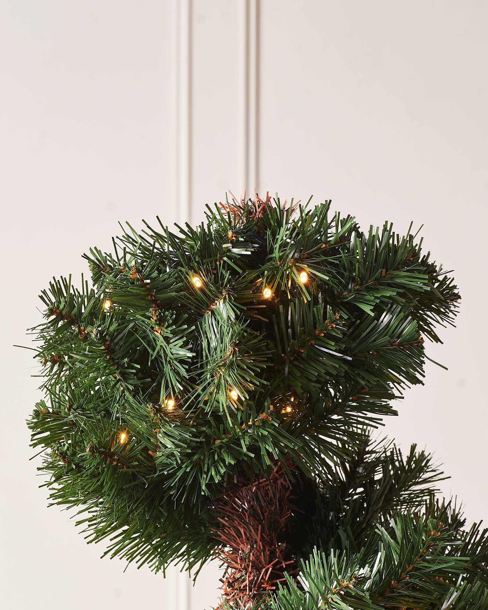 6-foot pre-lit spiral potted Christmas tree with a slender 41 cm diameter, featuring 400 PVC tips shaped in a modern spiral design. Decorated with warm white LED lights and red berries, displayed indoors in a stylish pot.