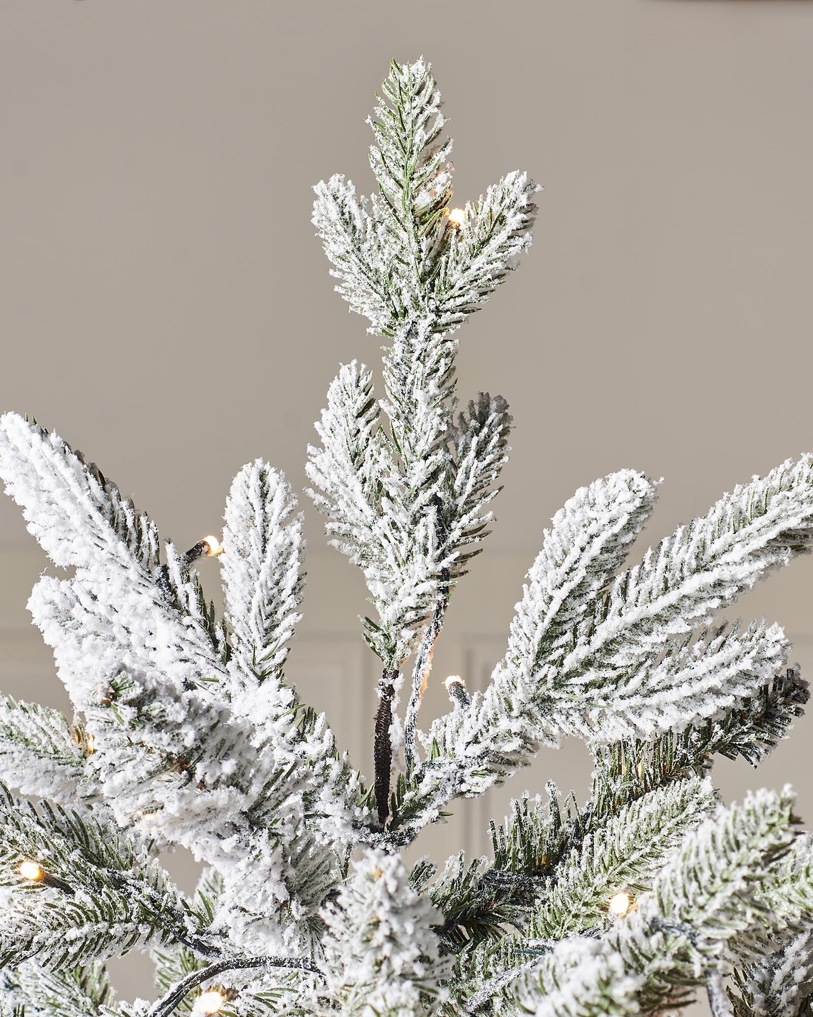 Pre-lit snow flocked Christmas tree with warm white LED lights and mixed PE and PVC branches, displayed against a white background. The tree features a realistic, snowy finish and multi-function lighting for a cozy festive look.