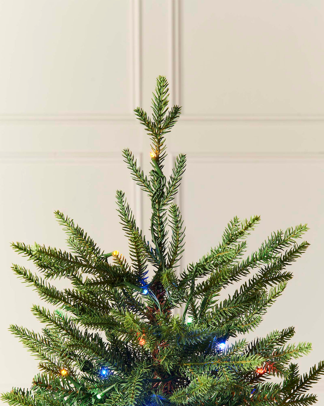 A 4 ft pre-lit potted pine Christmas tree with dense green foliage, dual warm white and multicolour LED lights, placed in a decorative pot indoors or outdoors.