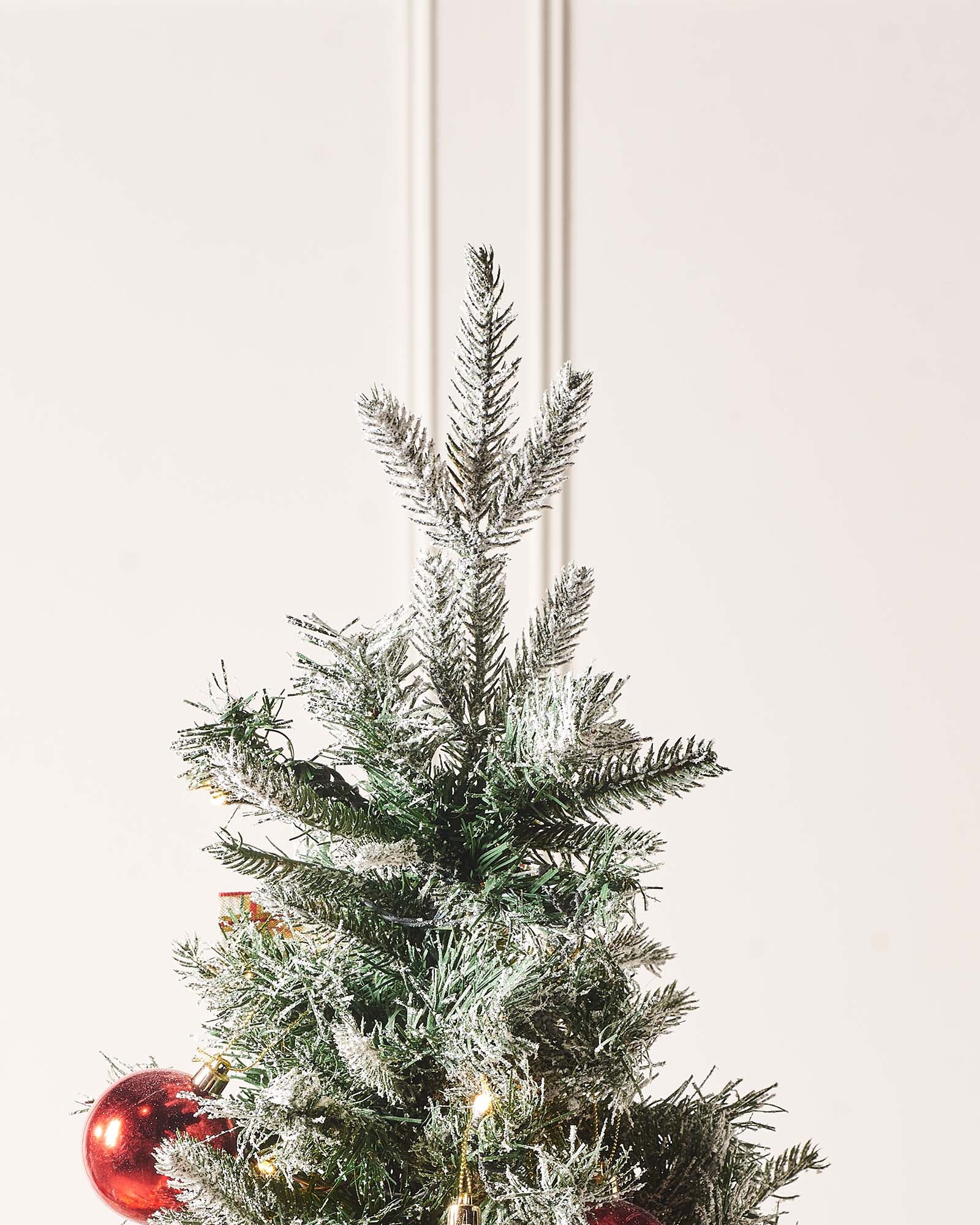 A 6-foot pre-lit pop-up artificial Christmas tree decorated with red and gold baubles and bows, featuring 100 warm white LED lights, displayed indoors with a white door in the background.