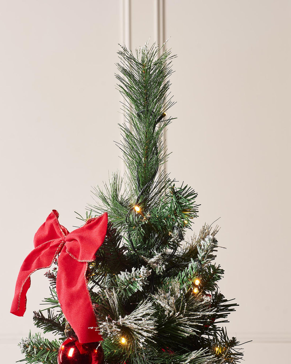 6-foot pre-lit pop-up decorated Christmas tree with 476 PVC tips, warm white LED lights, and red baubles and bows, placed indoors with a 3-meter lead wire.