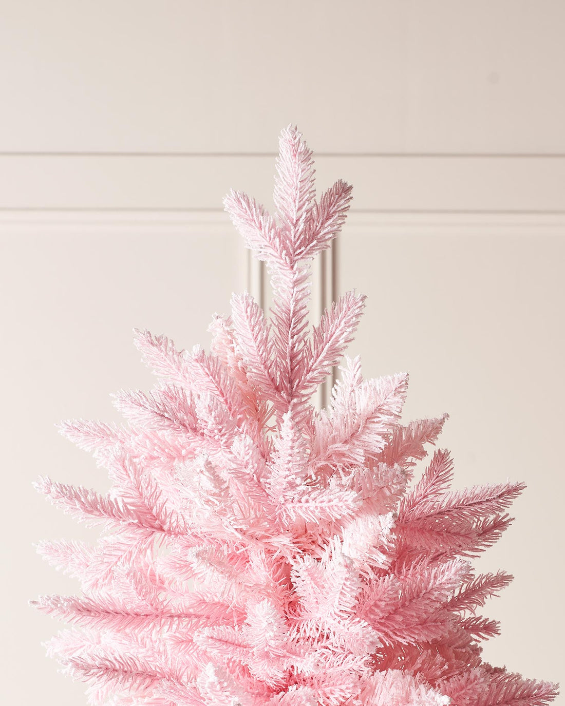 A 7-foot tall artificial pink Christmas tree with snow-flocked PE and PVC tips, set up in a room with white walls and a foldable base.