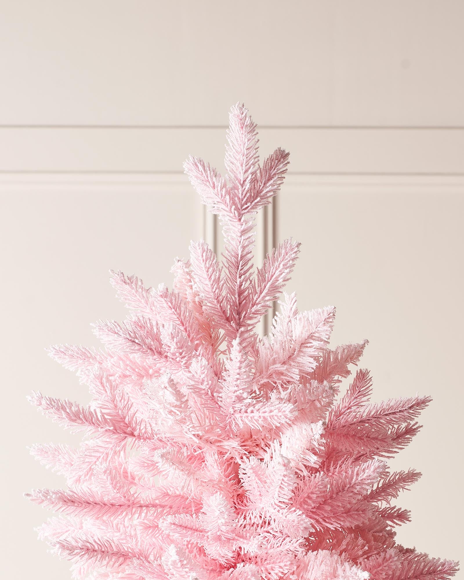 A 7-foot tall artificial pink Christmas tree with snow-flocked PE and PVC tips, set up in a room with white walls and a foldable base.