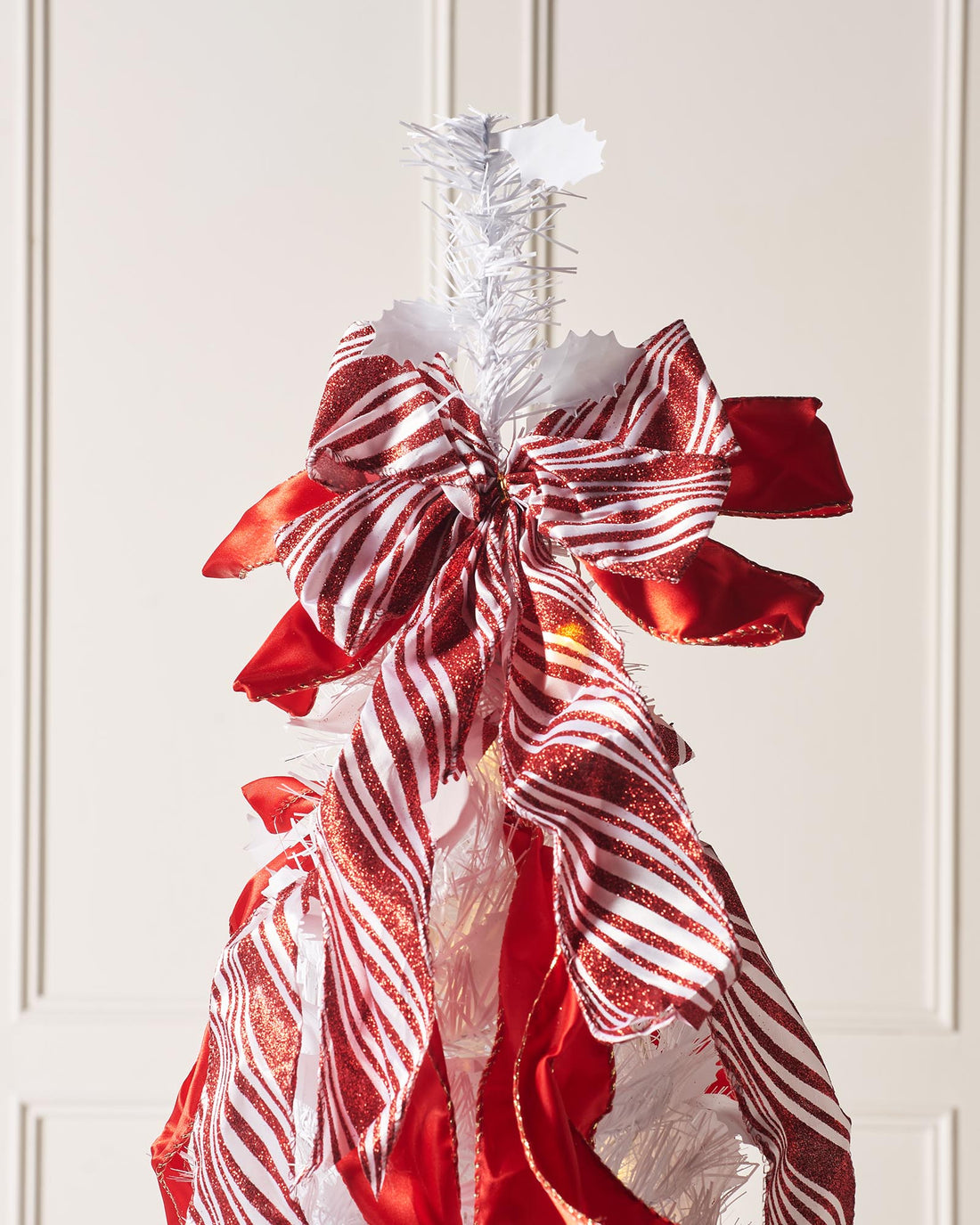 6-foot pre-lit pop-up Christmas tree with red and white decorations, including baubles and ribbons, illuminated by warm white LED lights.
