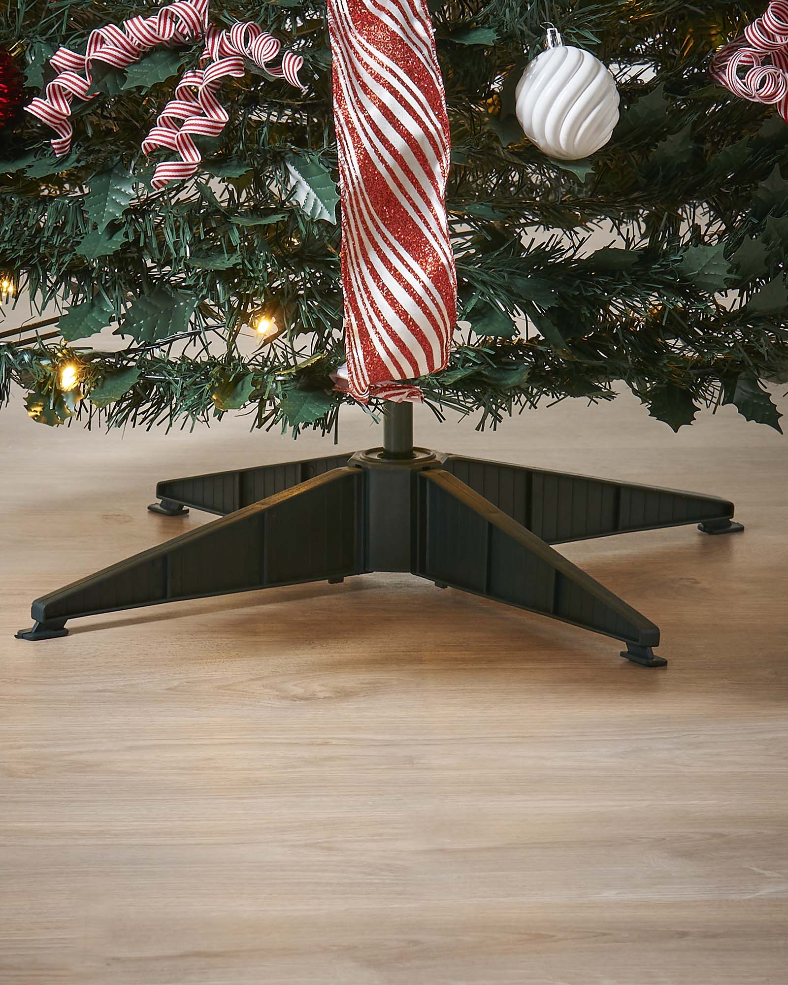 Decorated Christmas tree with ribbons and ornaments against a white paneled wall.