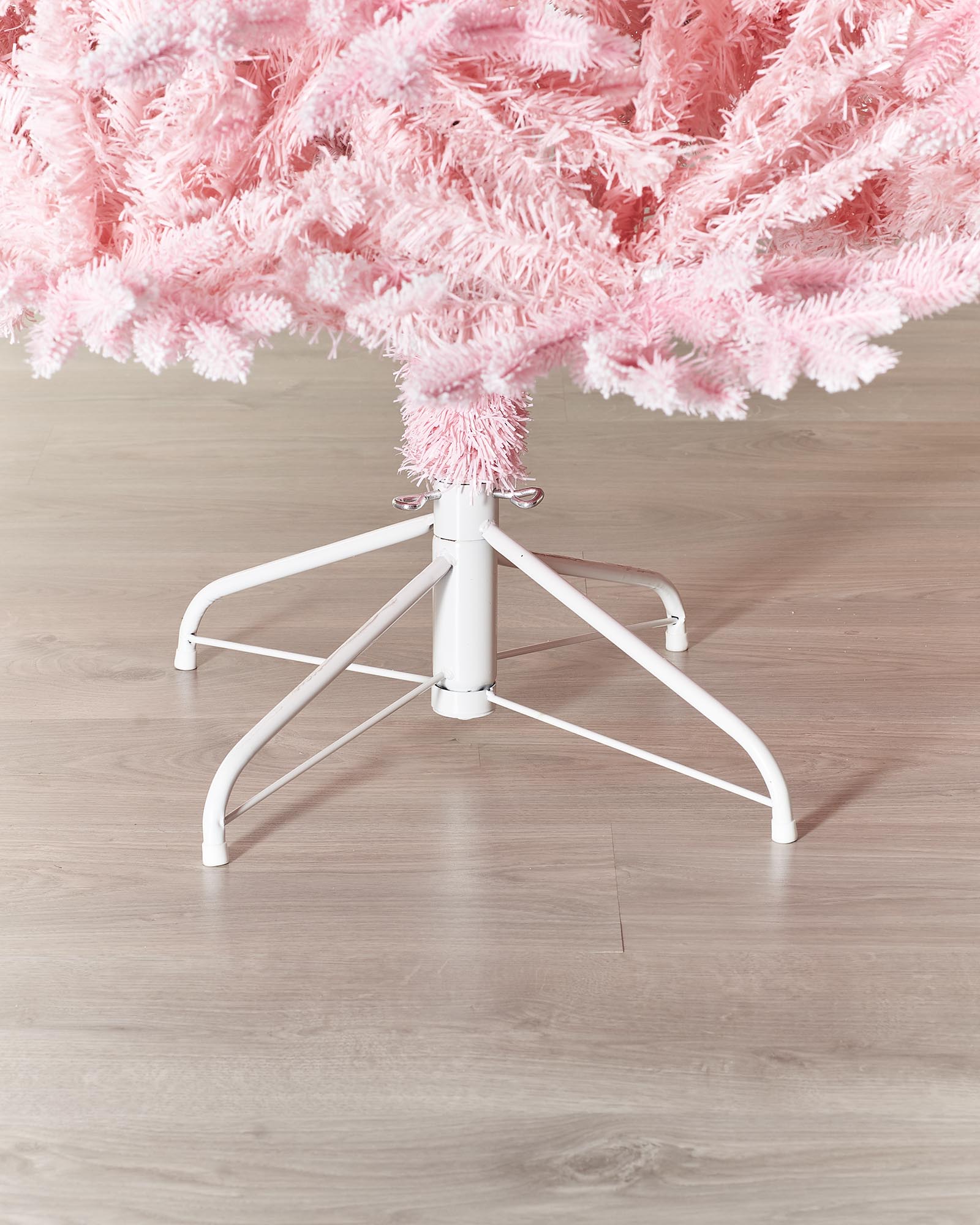 A 7-foot tall artificial pink Christmas tree with snow-flocked PE and PVC tips, set up in a room with white walls and a foldable base.