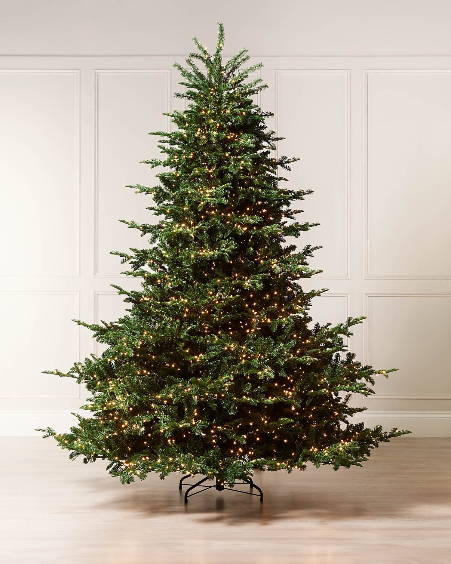 7.5ft pre-lit Noble Fir Christmas tree with warm white lights displayed indoors.