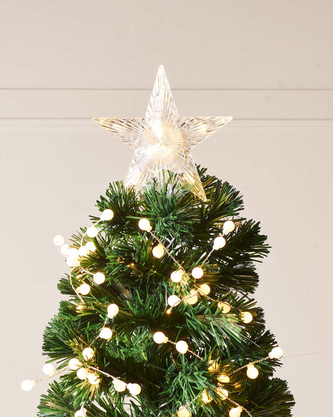 7-foot artificial Christmas tree with green fibre optic branches, white berry clusters, and warm white LED lights, topped with a glowing star—pre-lit and naturalistic, creating a rustic yet striking festive centerpiece against a plain background.