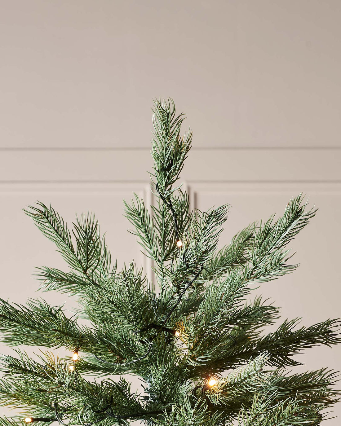 Pre-lit Colorado Blue Spruce Christmas tree with lifelike blue PE/PVC branches and built-in warm white LED lights, displayed indoors against a white wall—realistic texture, soft glow, and effortless festive elegance.