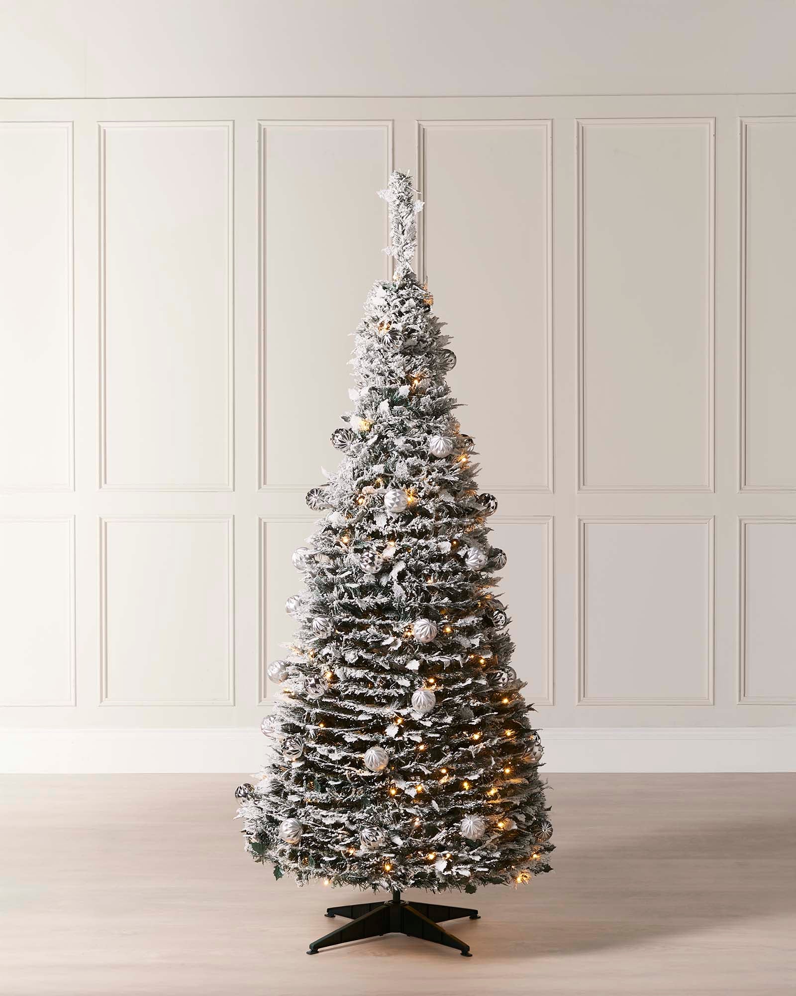 6 ft pre-lit decorated pop-up snow flocked Christmas tree with 150 warm white LEDs, white and silver baubles, and a snow-flocked finish—easy setup, creating a cozy indoor winter wonderland centerpiece.