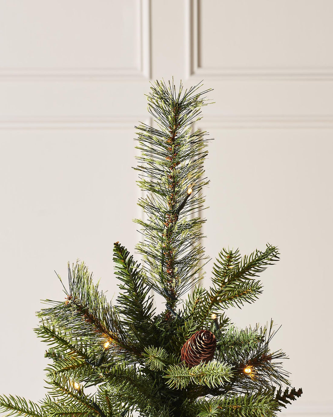 A 3.5-foot pre-lit natural pine potted Christmas tree with warm white LED lights and decorative berries, placed in a black potter