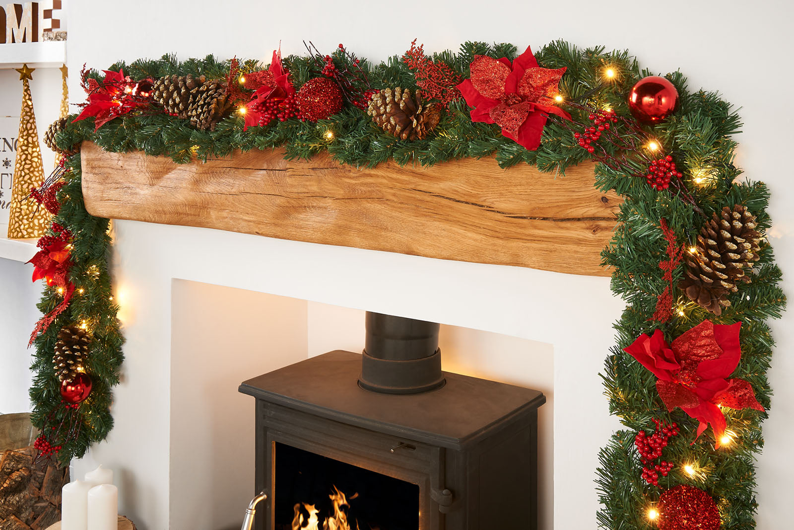 A close-up of a pre-lit extra thick decorated Christmas garland with red and gold elements, including berries, pine cones, baubles, and glittery decorations, illuminated by warm white LED lights.