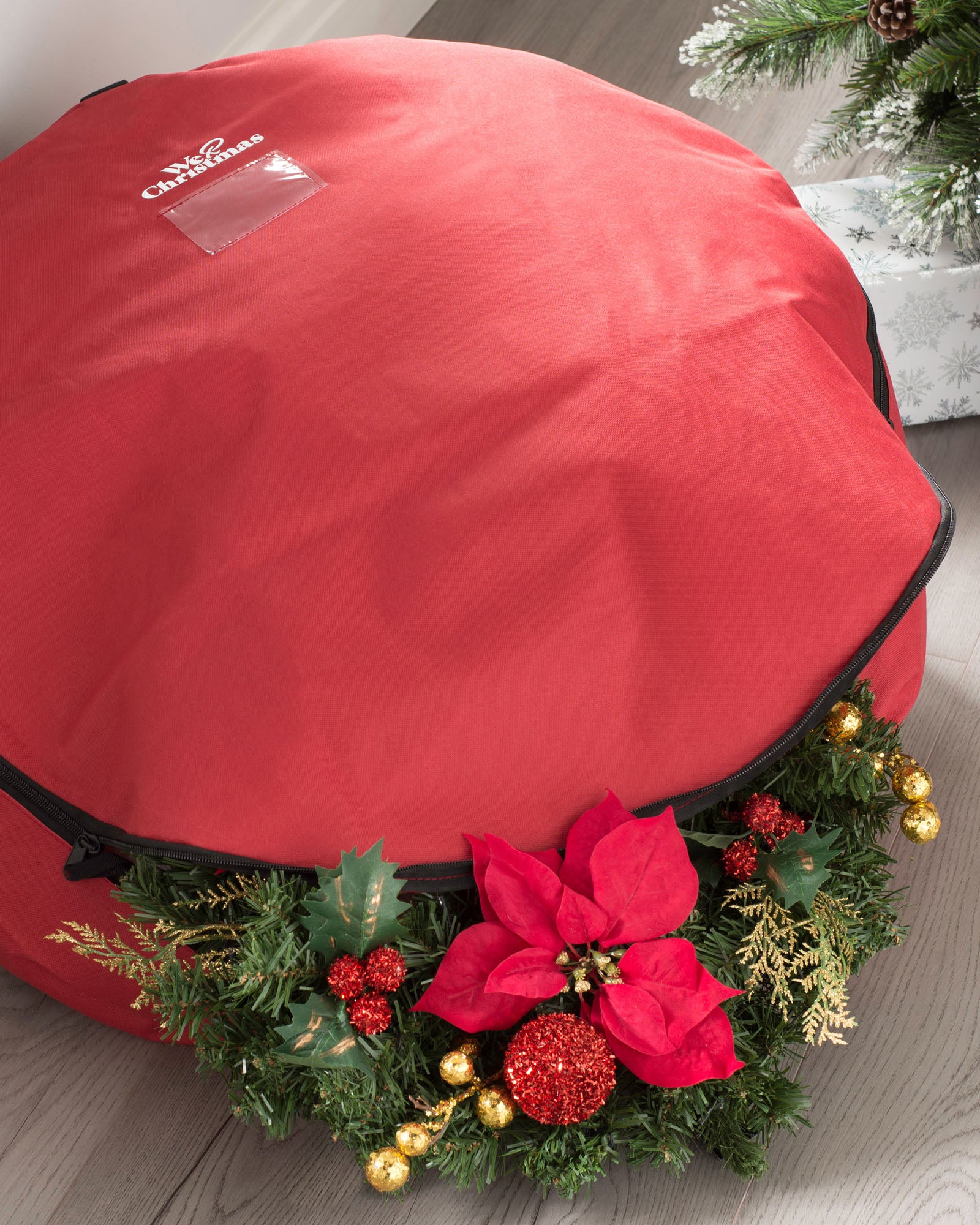 A red, round, waterproof storage bag for garlands and wreaths, adorned with festive decorations like a poinsettia, pine branches, and ornaments.