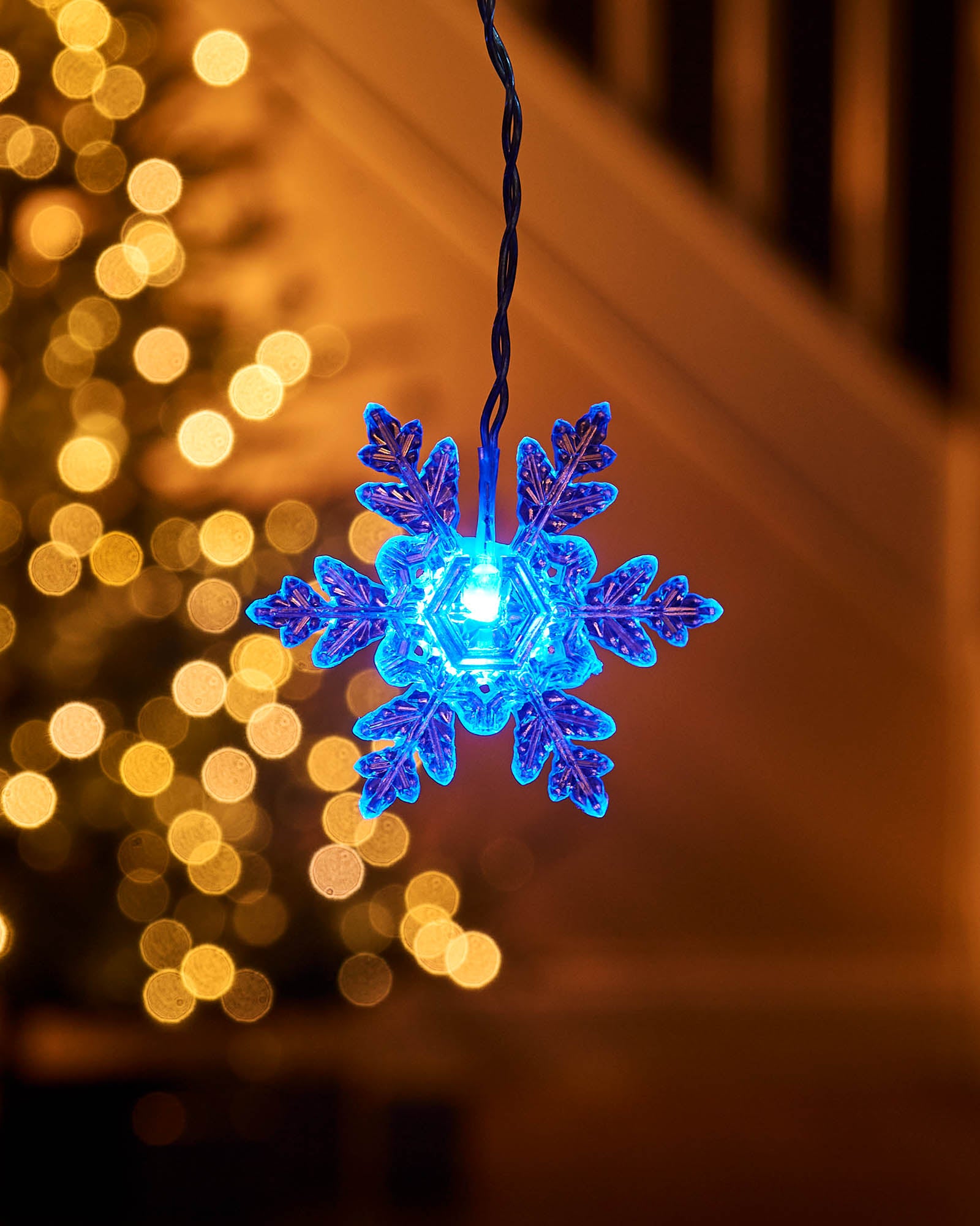 Close-up of a blue LED snowflake light hanging on a curtain light strand