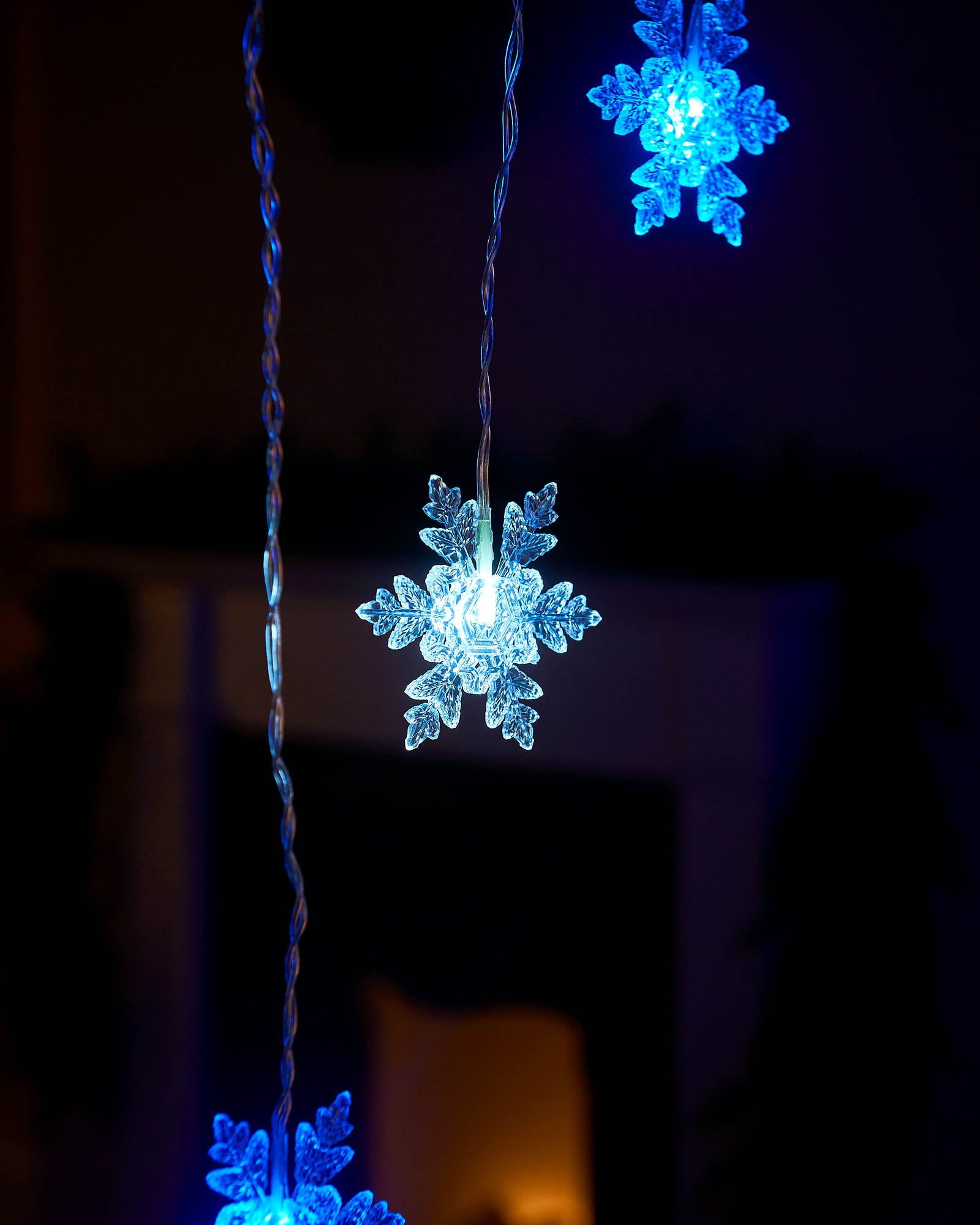 Blue and white snowflake curtain lights hanging at different heights