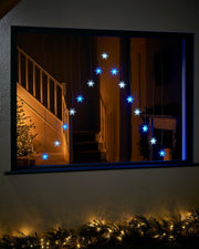Blue and white snowflake curtain lights displayed in a large window