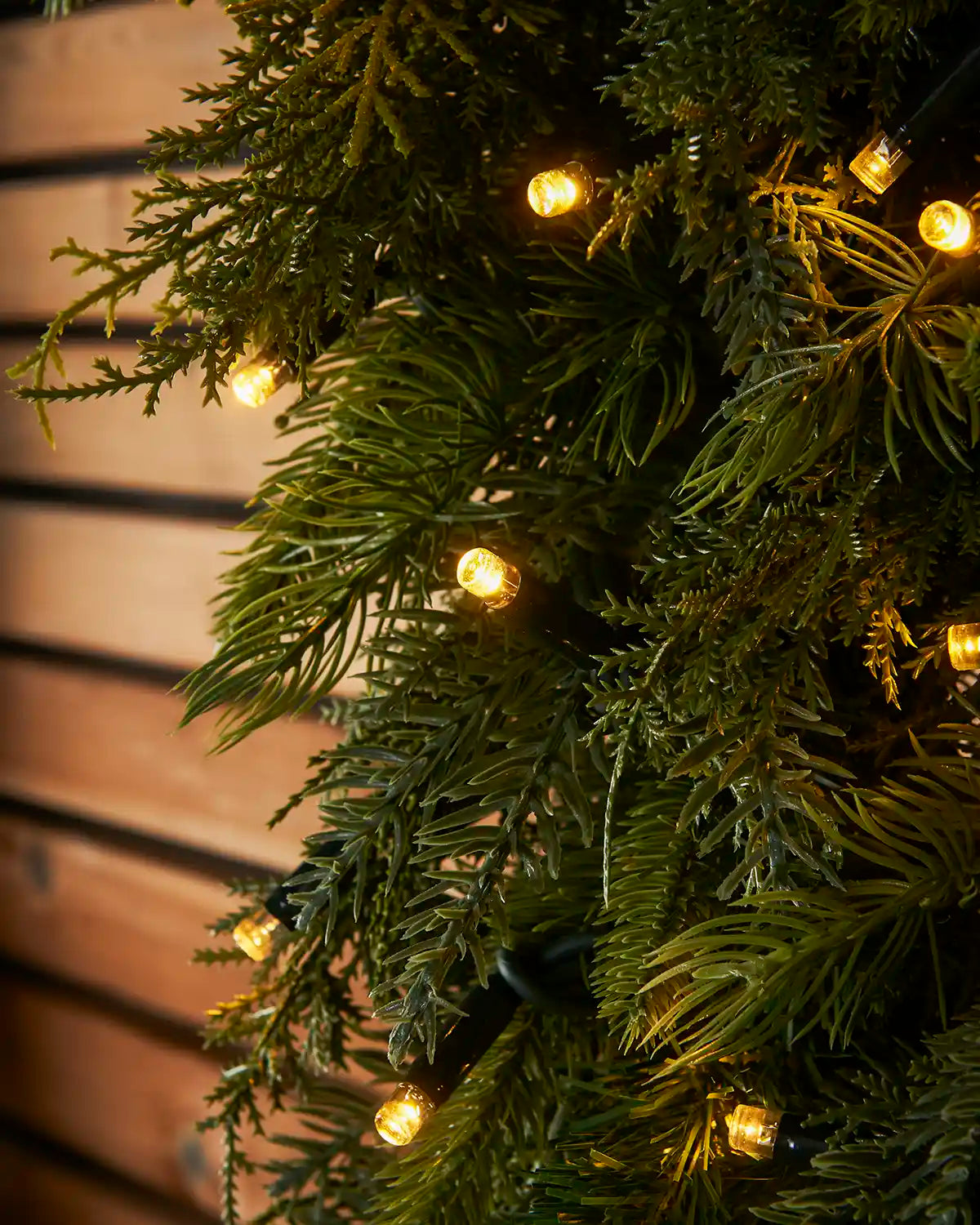 Close-up of warm white LED lights nestled in realistic green fir foliage.