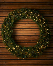 1.2m pre-lit natural fir wreath with warm white LEDs on a wooden wall.