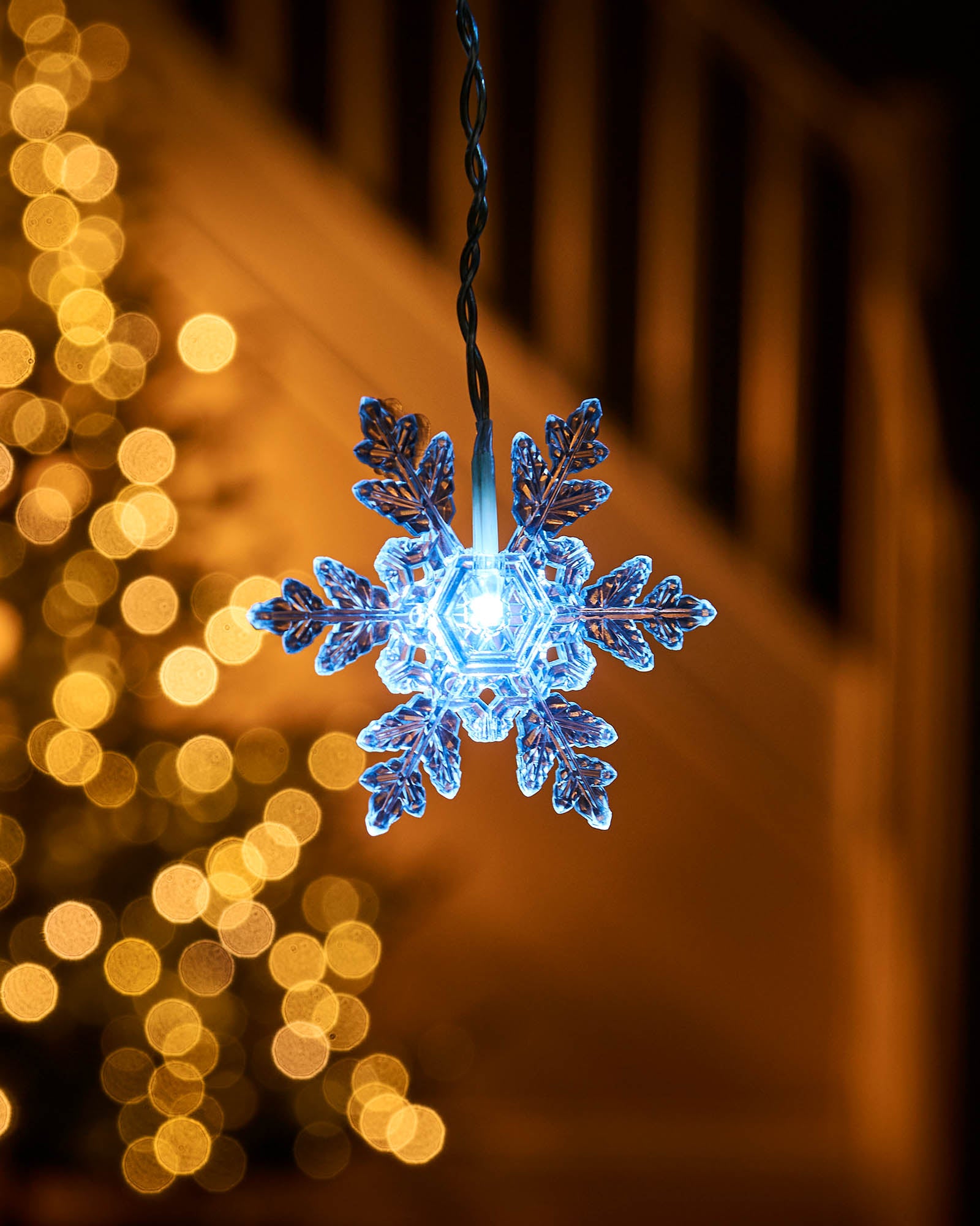 Close-up of a white LED snowflake light hanging on a curtain light strand