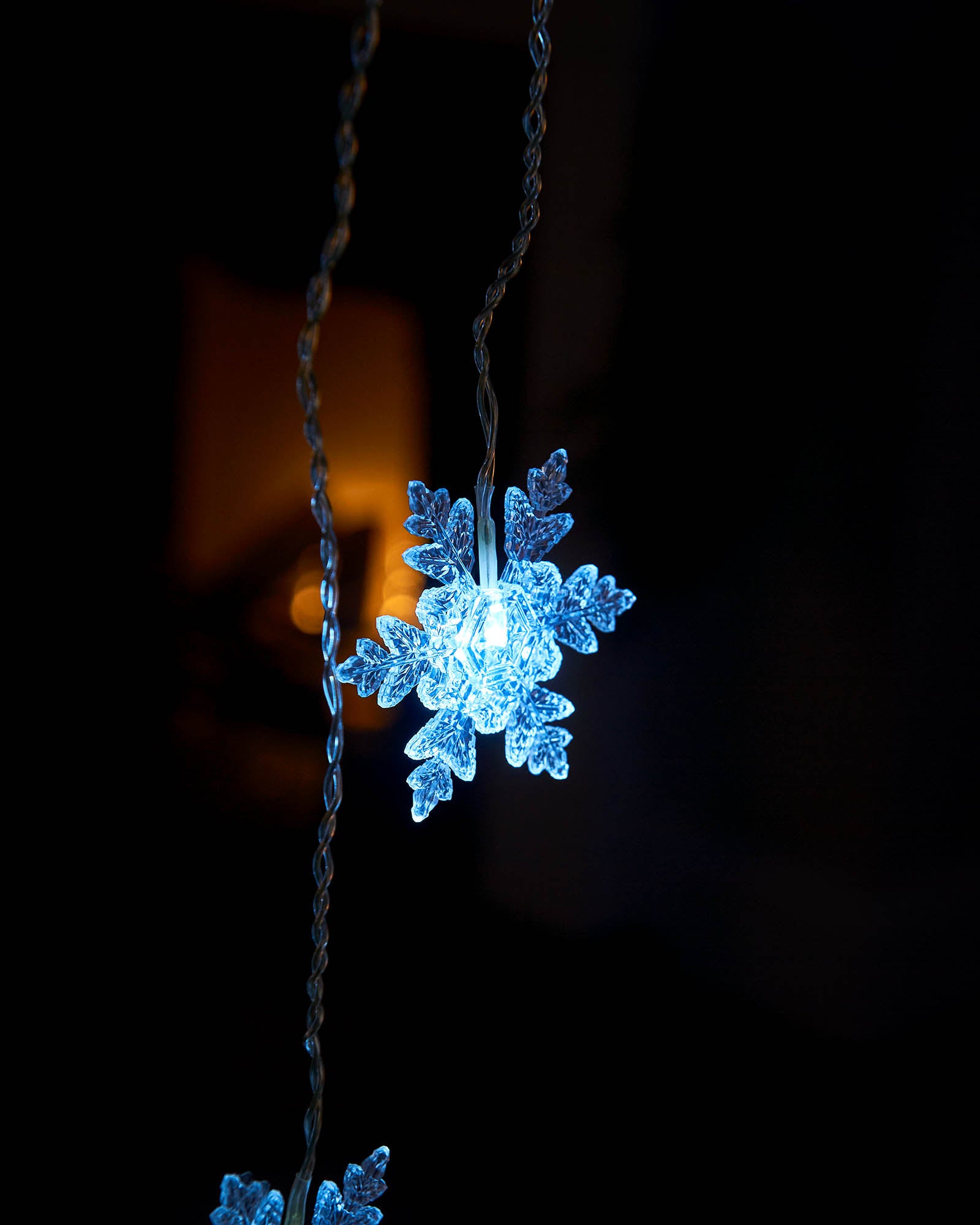 Close-up of an illuminated white snowflake on a hanging curtain light