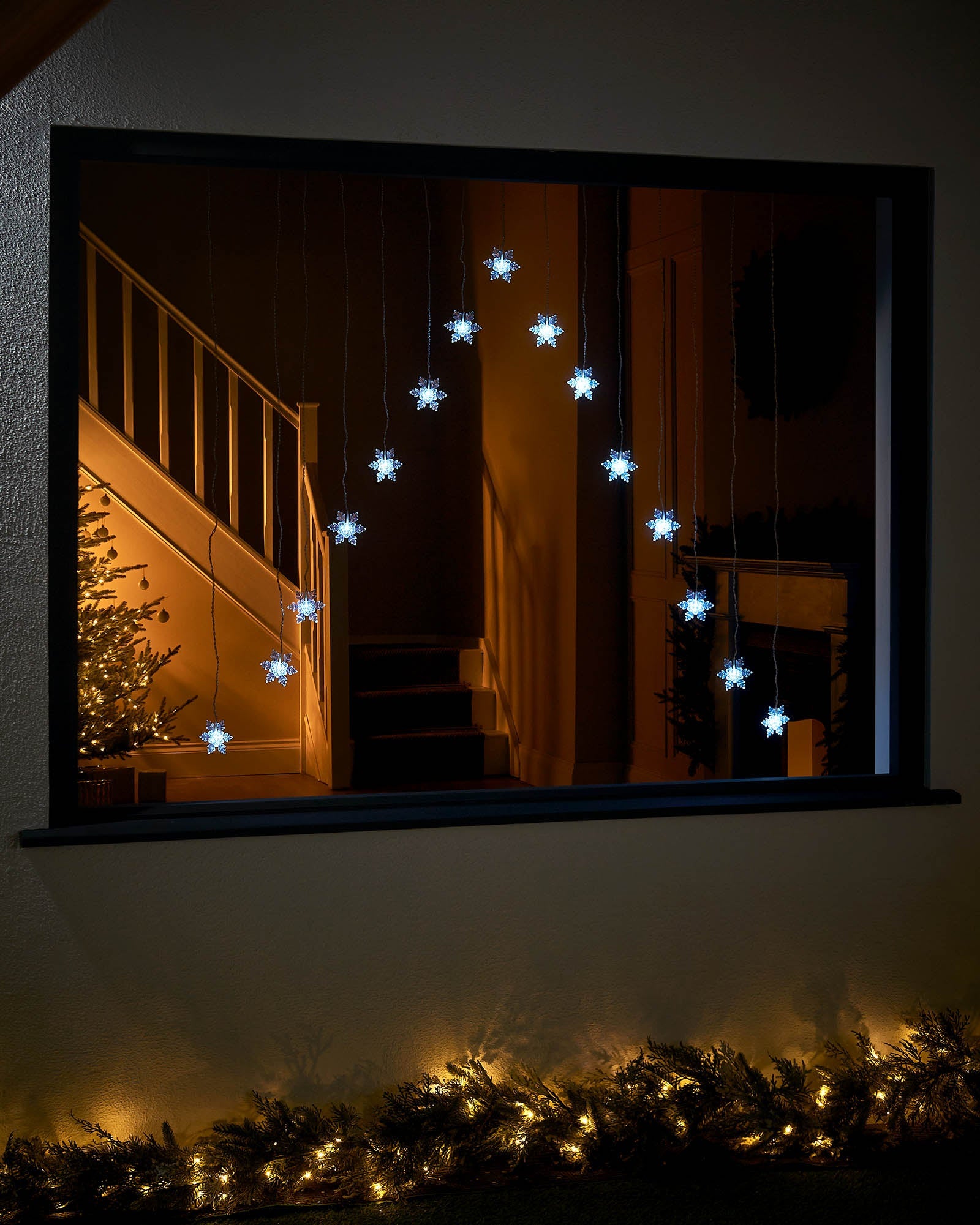 White snowflake curtain lights displayed in a large window