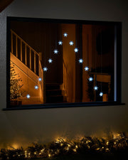 White snowflake curtain lights displayed in a large window
