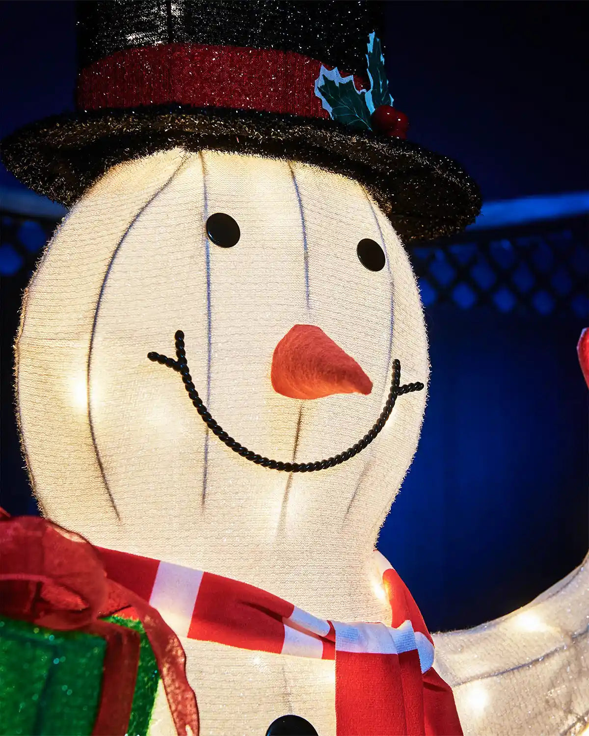 Close-up of the 100cm pre-lit snowman’s smiling face, black top hat and striped scarf.