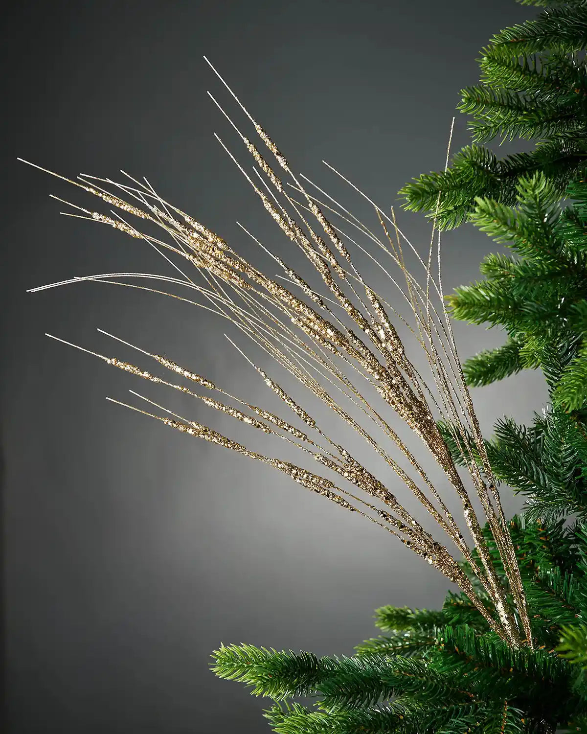 100cm gold glitter wispy spray attached to Christmas tree in front of grey background 