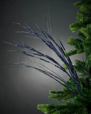 Full image of 100cm navy blue glitter wispy tree spray attached to Christmas tree in front of grey wall background