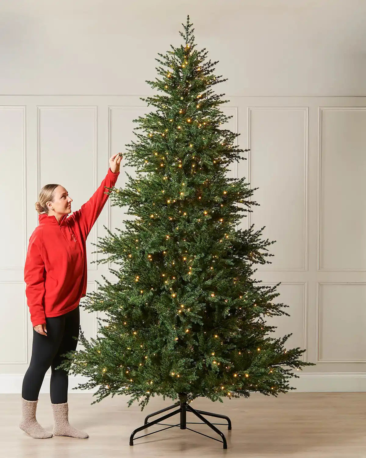 10ft pre-lit Traditional Fir Christmas tree with warm white lights shown indoors beside a person for scale.